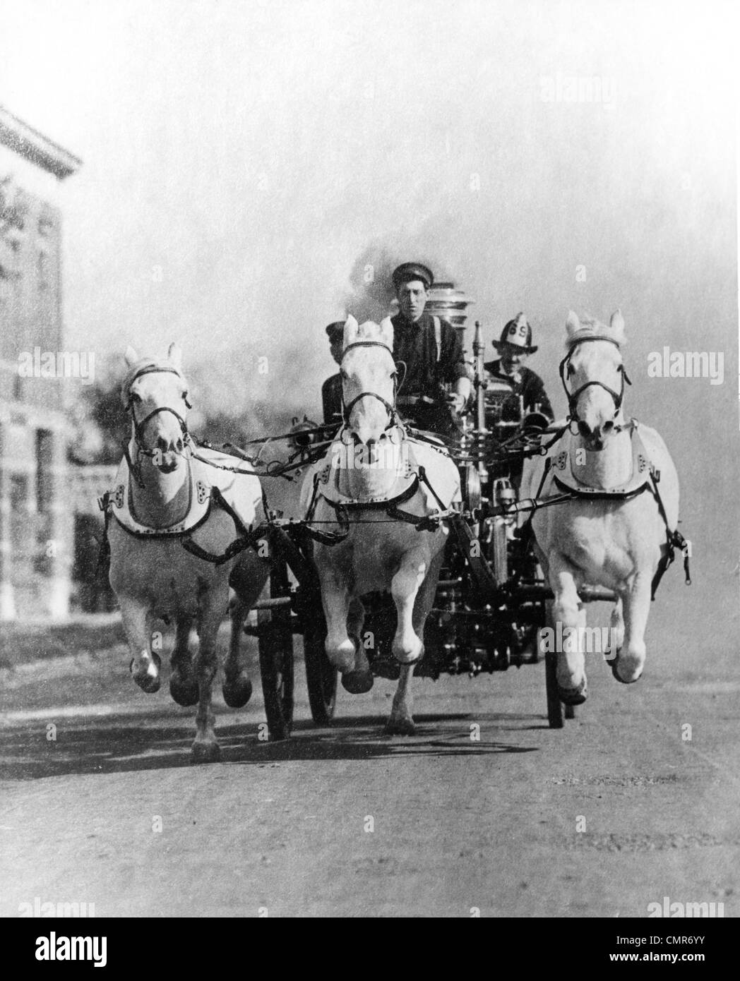 1890s 1900s OLD-TIME HEAD-ON SHOT OF HORSE-DRAWN FIRE TRUCK RACING DOWN STREET Stock Photo