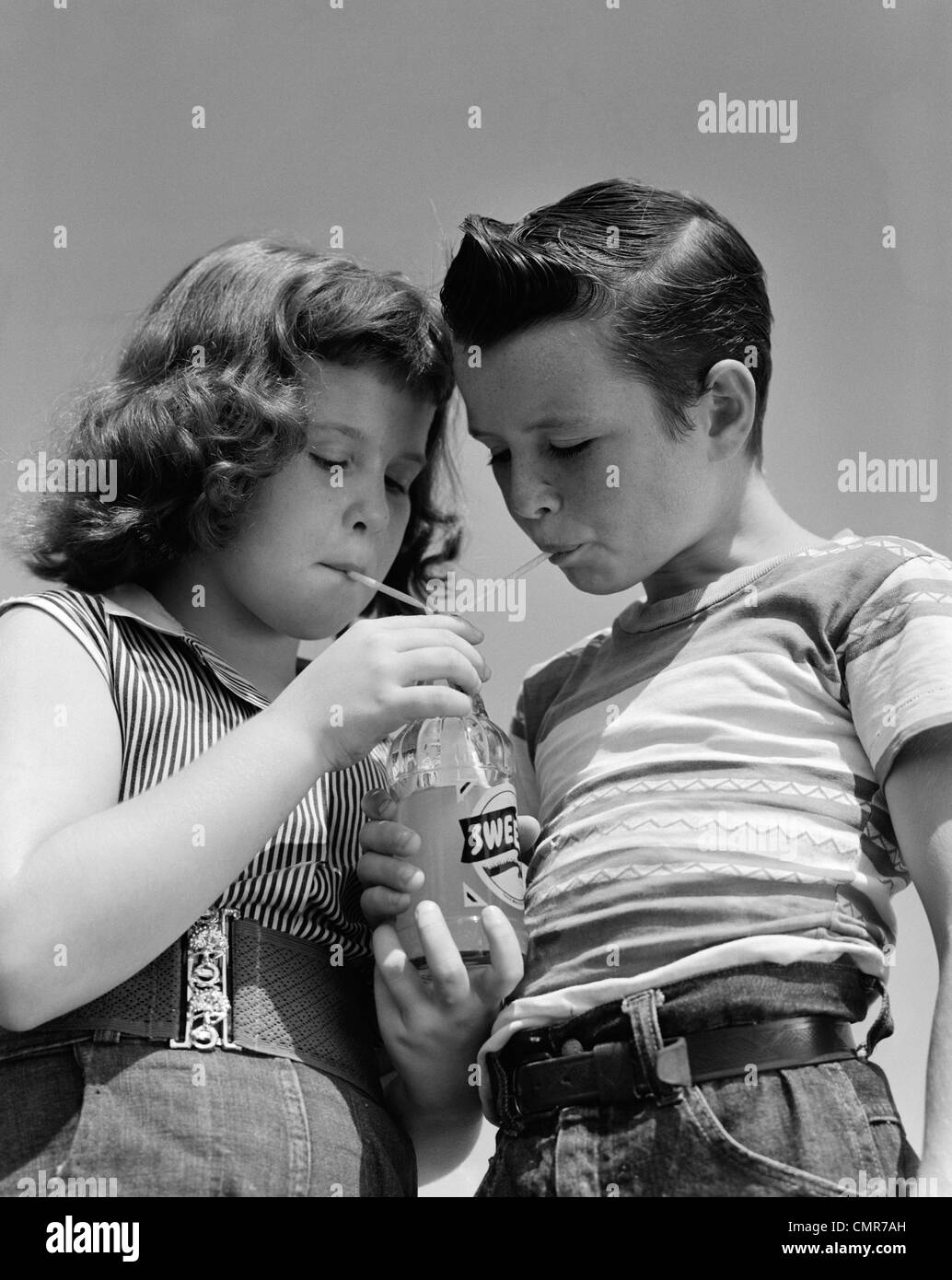 1950s GIRL AND BOY SHARE SODA TWO STRAWS SUMMER OUTDOOR Stock Photo
