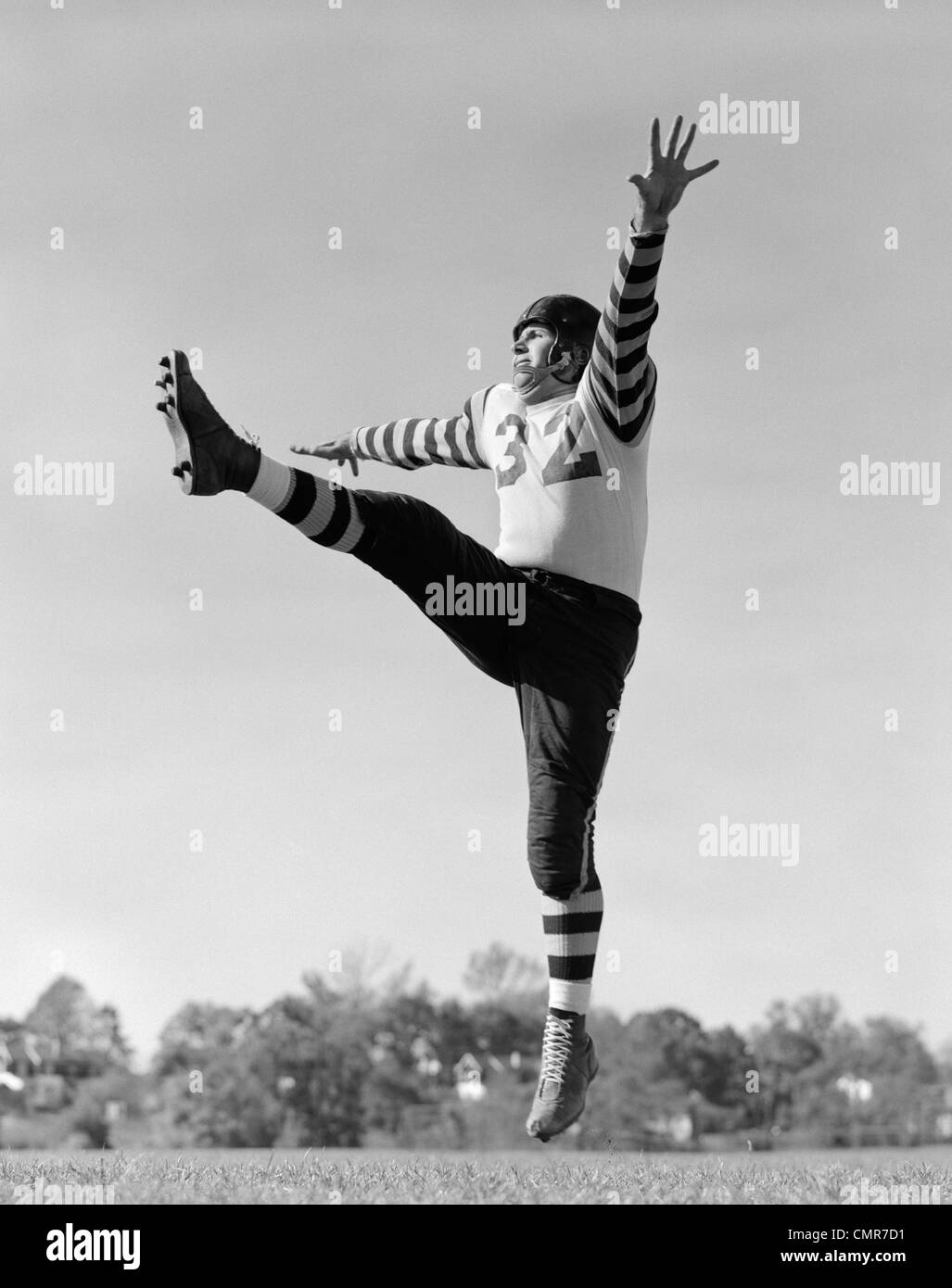 1930s FOOTBALL KICKER IN UNIFORM WITH STRIPED SLEEVES WITH LEG IN AIR & OTHER FOOT OFF OF GROUND Stock Photo