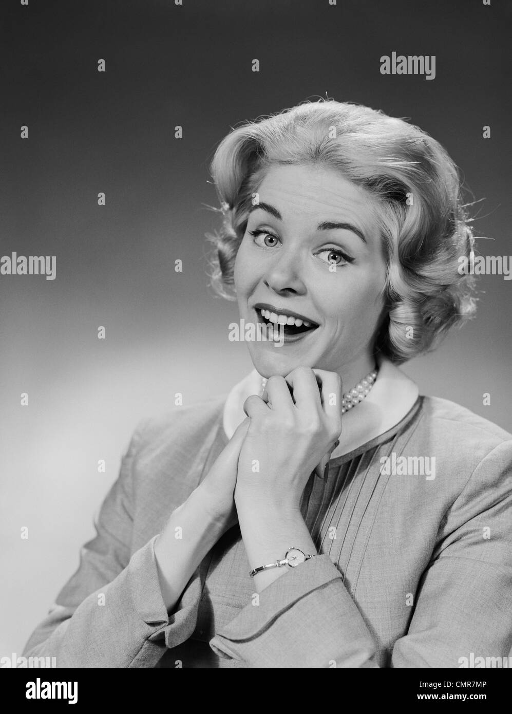 1950s 1960s WOMAN CLASPED HAND BY CHIN WITH WISHFUL HOPING HAPPY JOYFUL FACIAL EXPRESSION Stock Photo