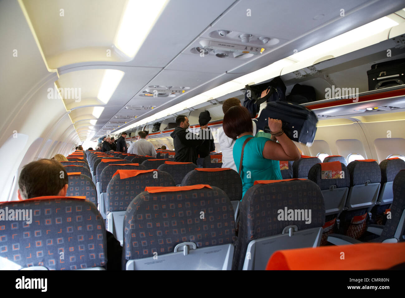 passengers placing bags in overhead lockers of easyjet aircraft at belfast international airport northern ireland uk. Stock Photo