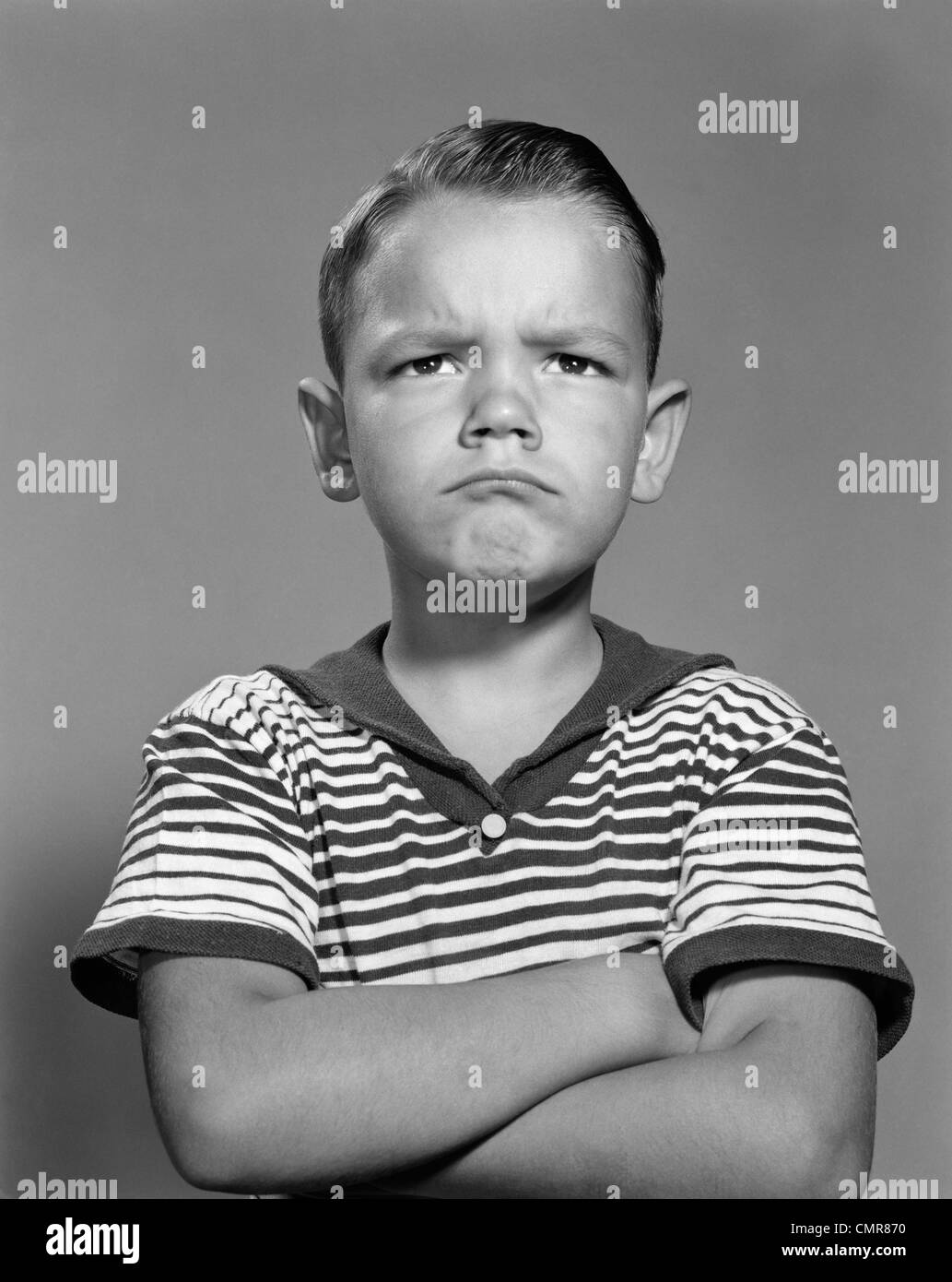 1960s PORTRAIT POUTING ANGRY BOY ARMS FOLDED AGAINST CHEST STRIPED SHIRT Stock Photo
