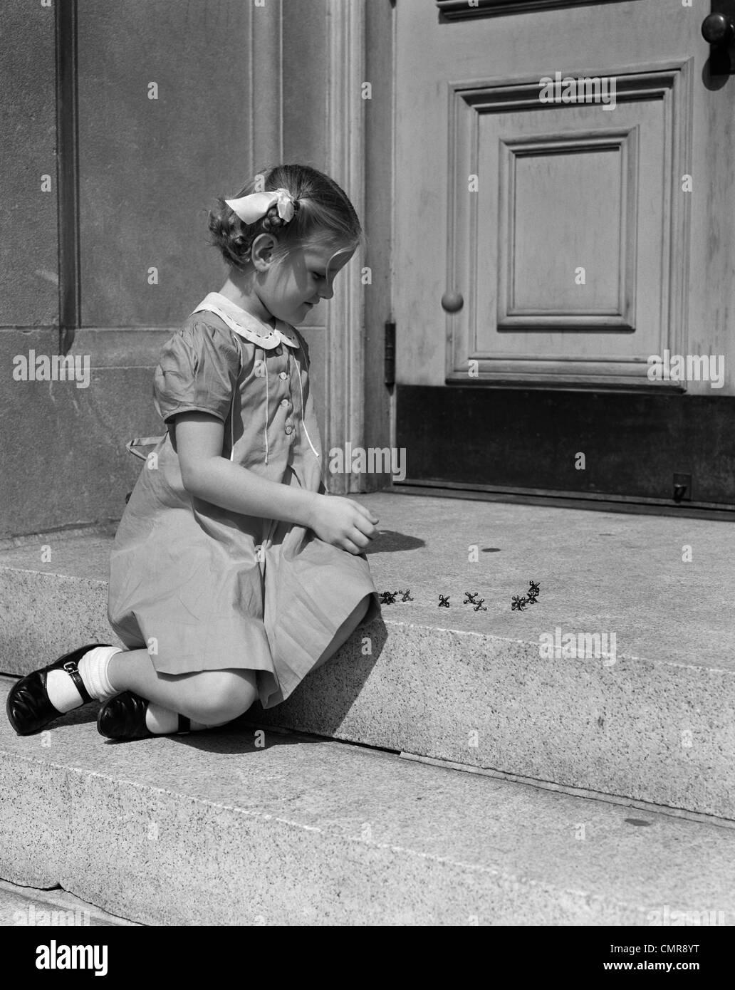 1930s 1940s CHILD LITTLE GIRL SITTING ON STOOP PLAYING JACKS Stock Photo