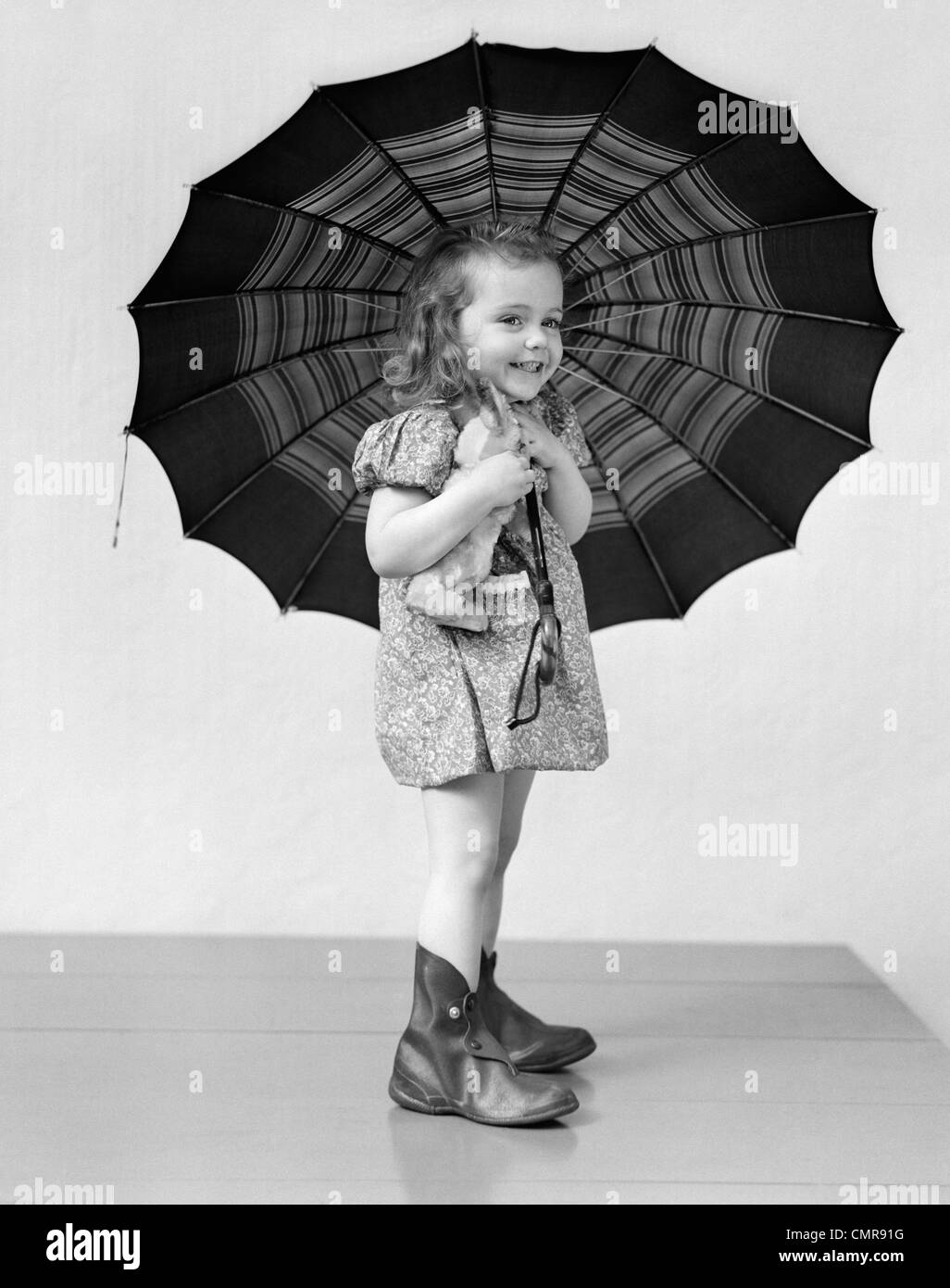 1930s 1940s CHILD SMILING LITTLE GIRL HOLDING RAINY DAY UMBRELLA Stock Photo