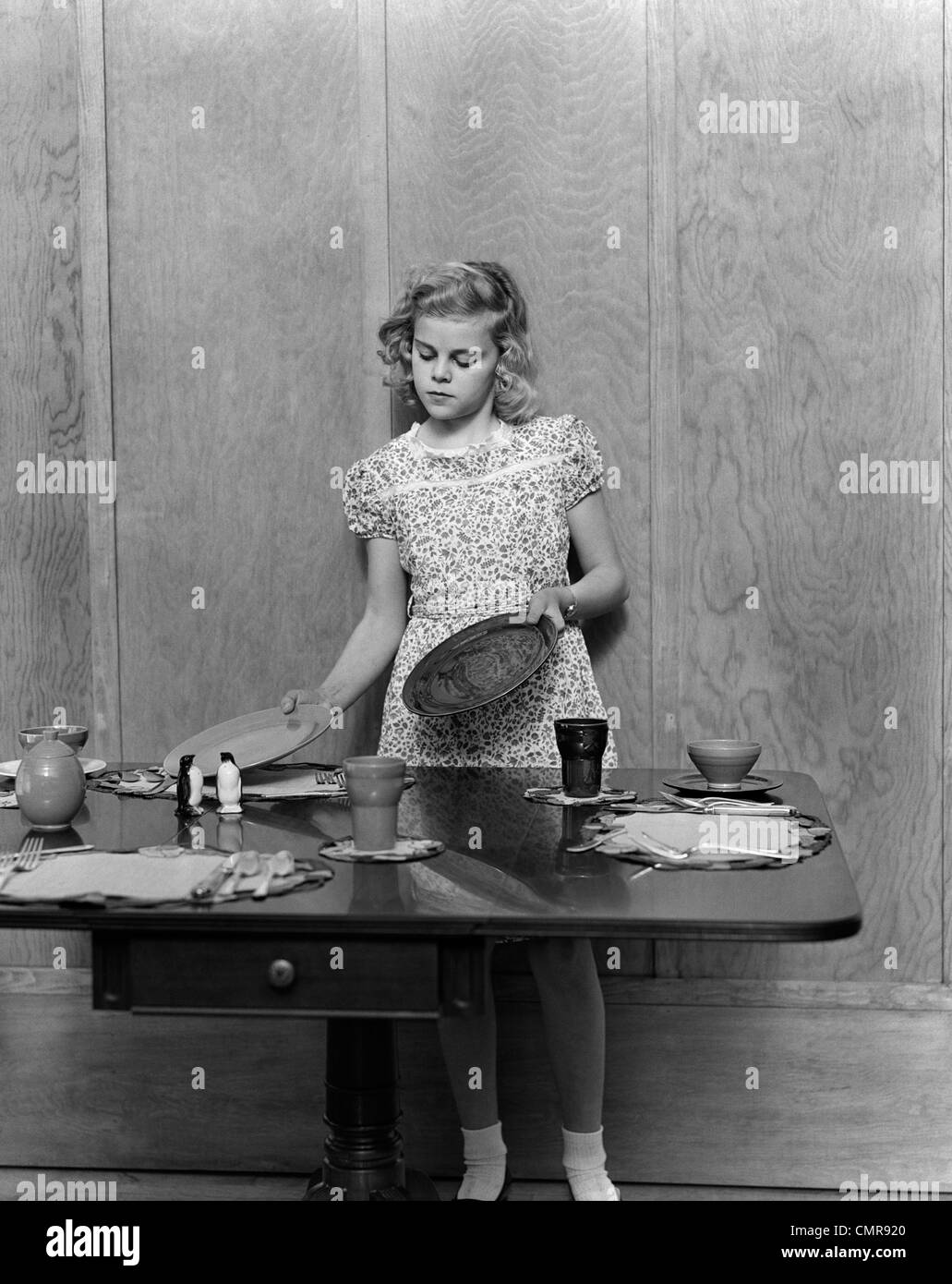 1940s BLOND PRE-TEEN YOUNG WOMAN SETTING TABLE Stock Photo