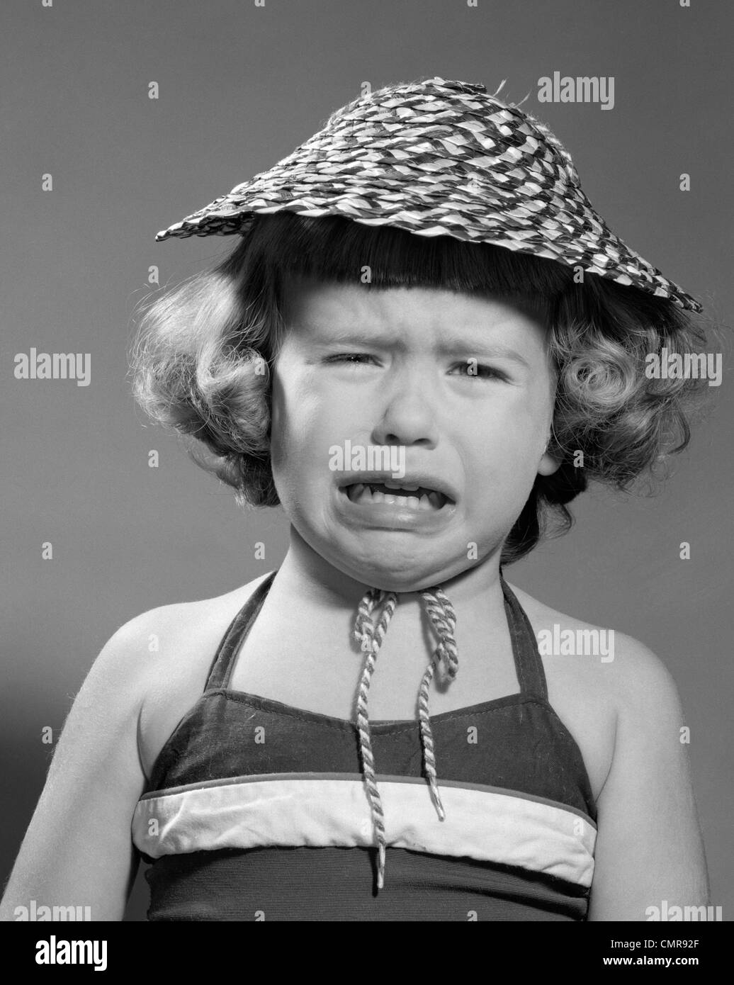 1960s PORTRAIT OF GIRL WEARING STRAW HAT AND CRYING Stock Photo