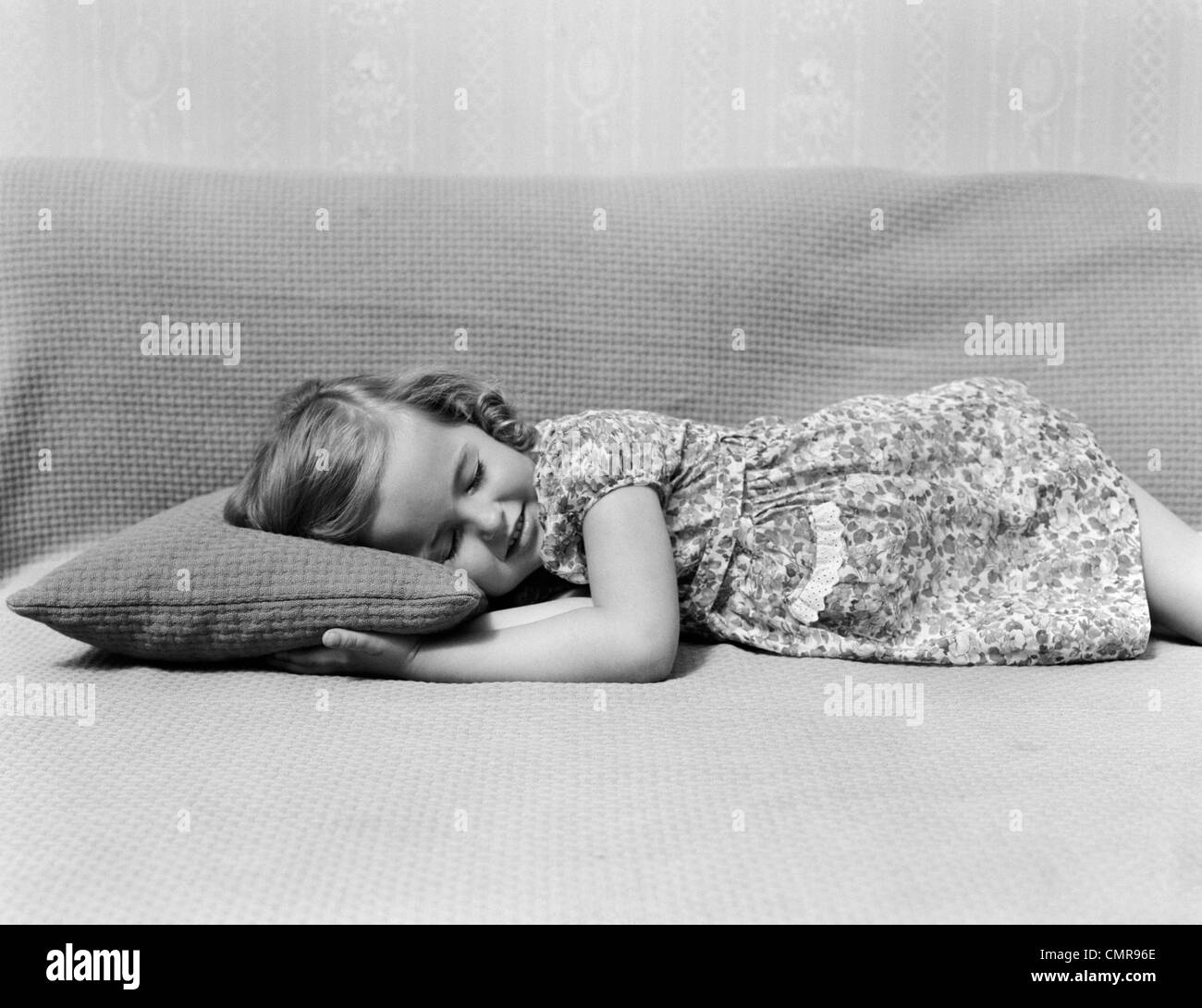 1940s CHILD LITTLE GIRL NAPPING SLEEPING ON COUCH PILLOW Stock Photo