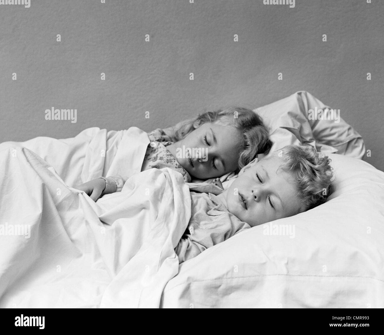 1940s TWO CHILDREN BOY AND GIRL SLEEPING IN BED Stock Photo