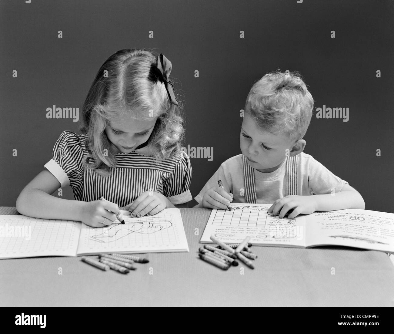 1940s TWO CHILDREN COLORING DRAWING IN BOOK Stock Photo