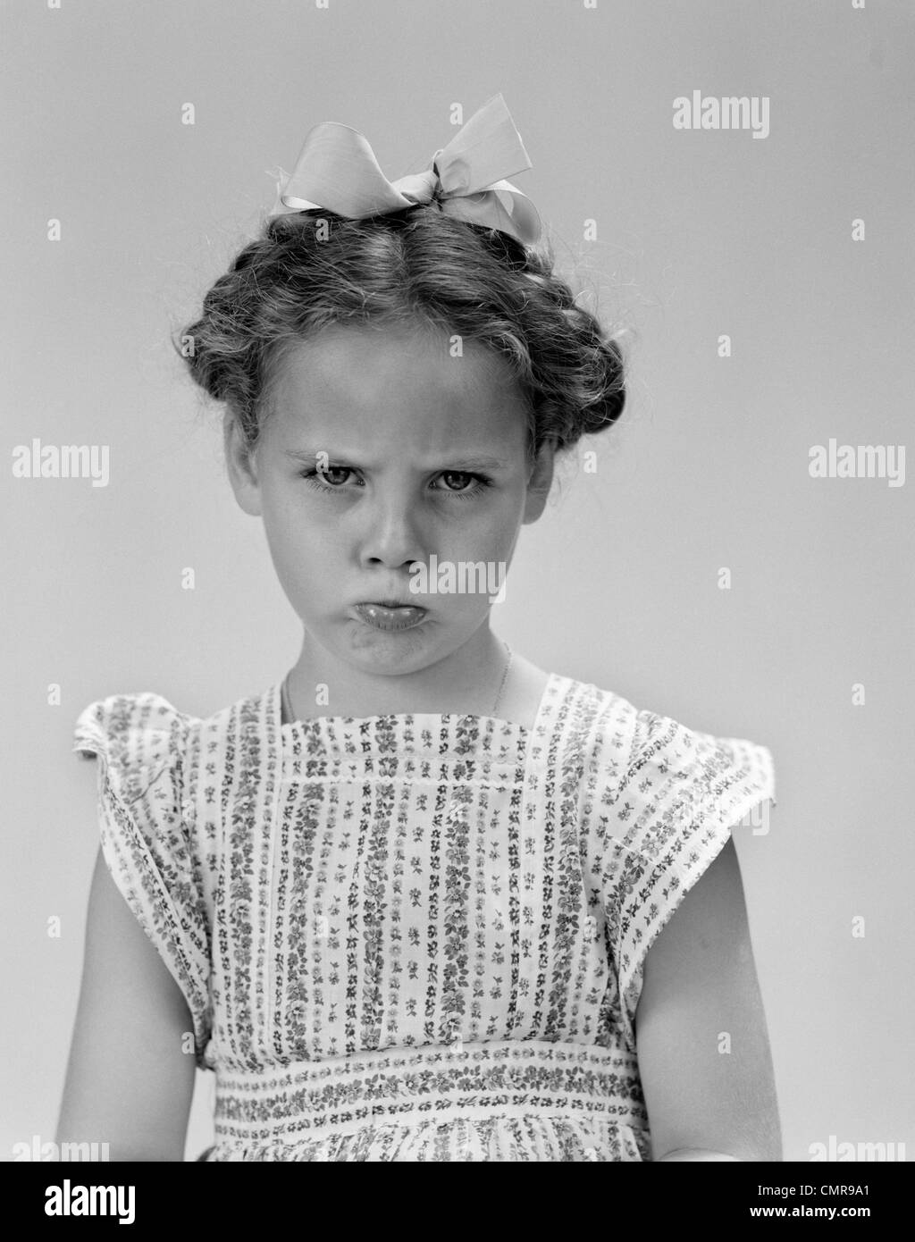 1940s LITTLE GIRL LOOKING SAD POUTING FROWNING LOOKING AT CAMERA Stock Photo