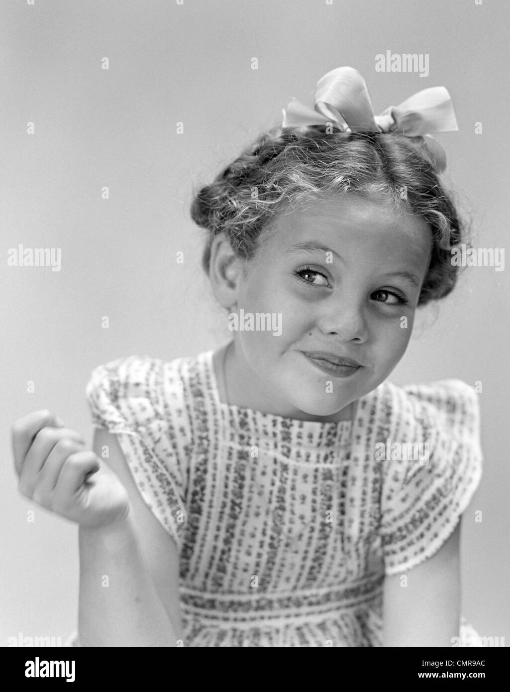1940s LITTLE GIRL SMILING SMIRKING LOOKING OFF TO ONE SIDE Stock Photo
