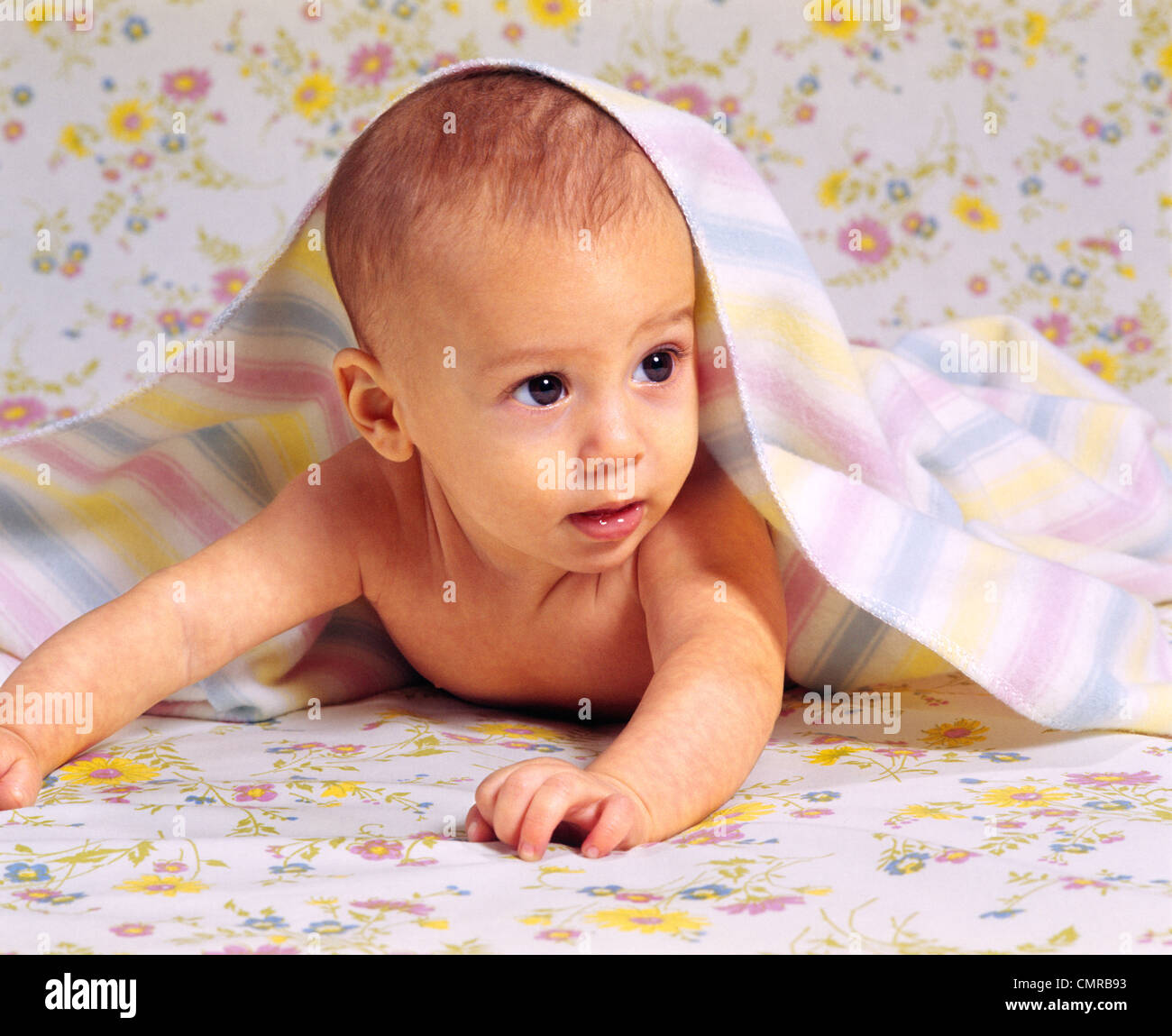 1970s ALERT BABY CRAWLING WITH BLANKET DRAPED OVER HEAD AND SHOULDERS