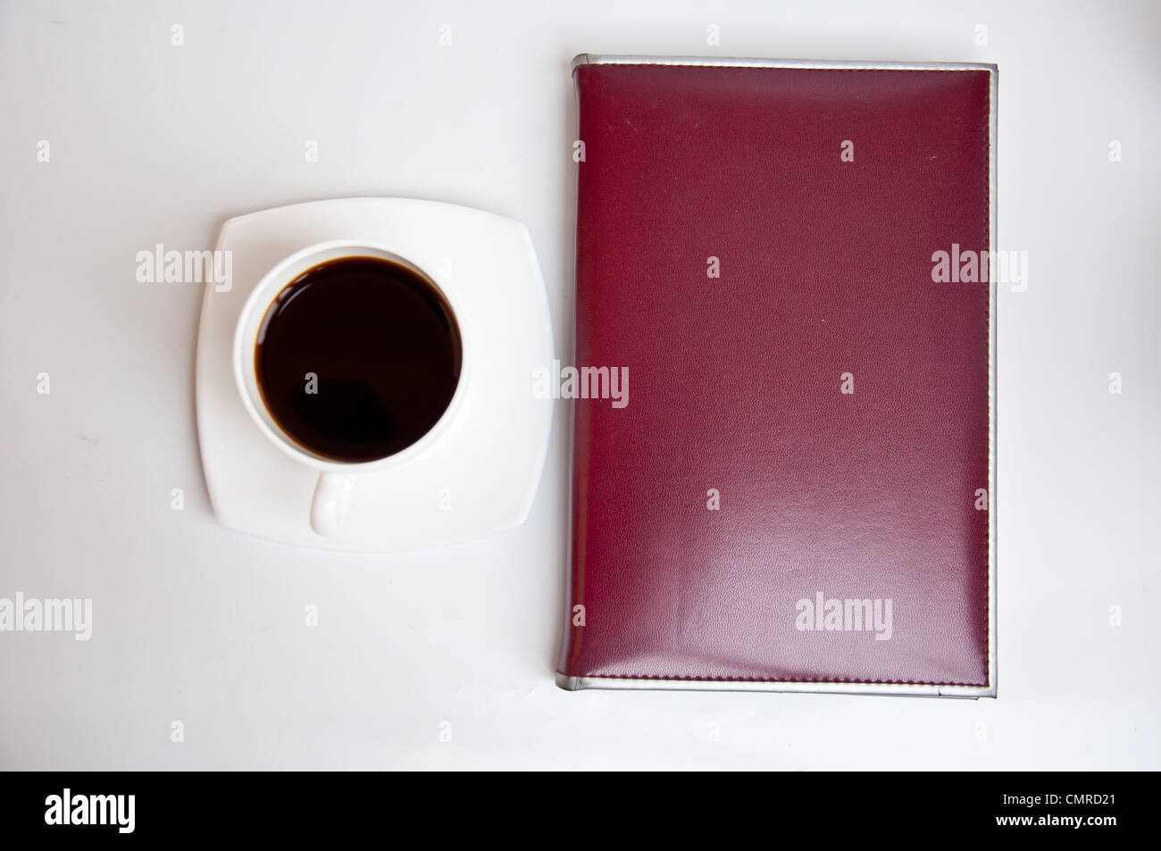 brown notebook and black coffee on white background Stock Photo