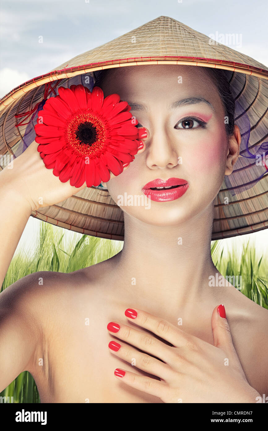 Beautiful Vietnamese girl in a traditional hat is holding flowers Stock