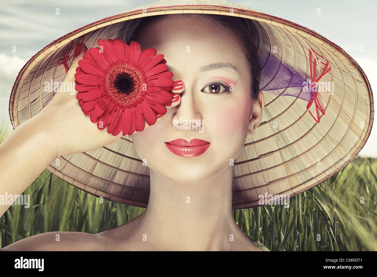 Beautiful Vietnamese girl in a traditional hat is holding flowers Stock
