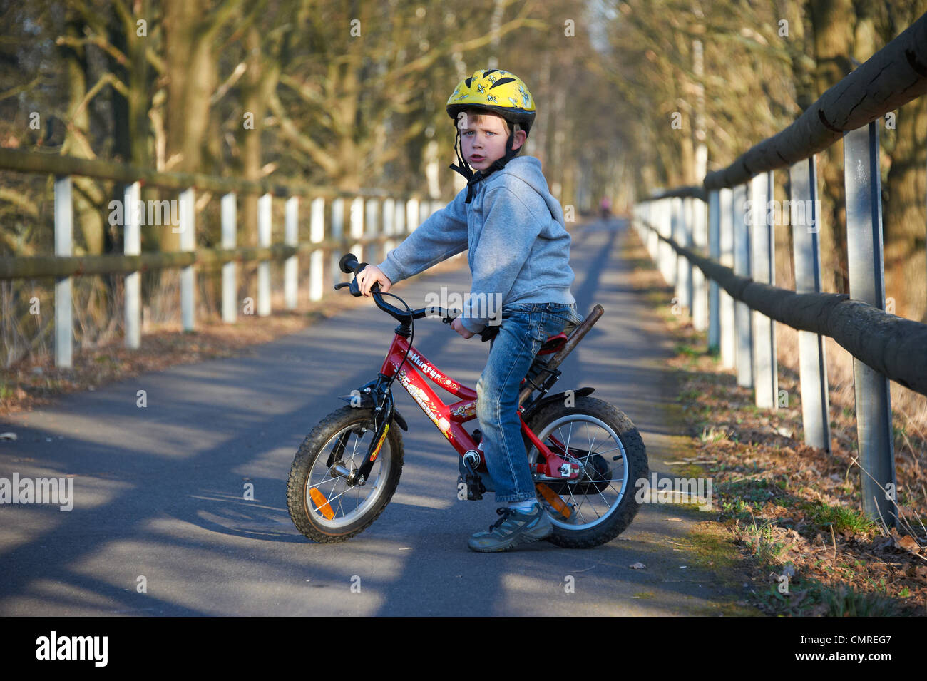 Child blond boy 5 years old riding bicycle with safety helmet in