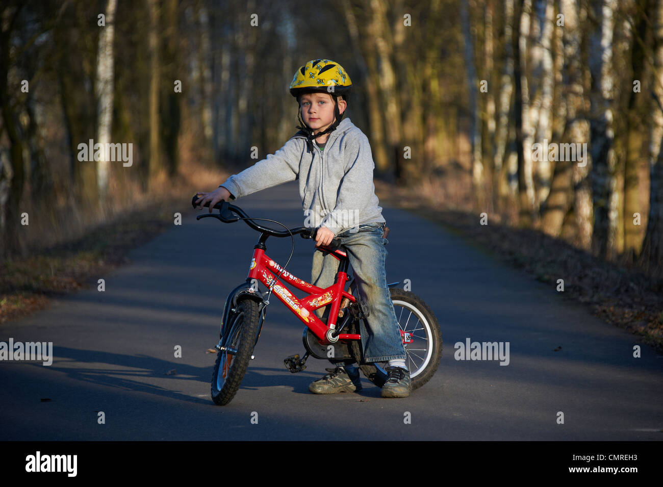 Child blond boy 5 years old riding bicycle with safety helmet in
