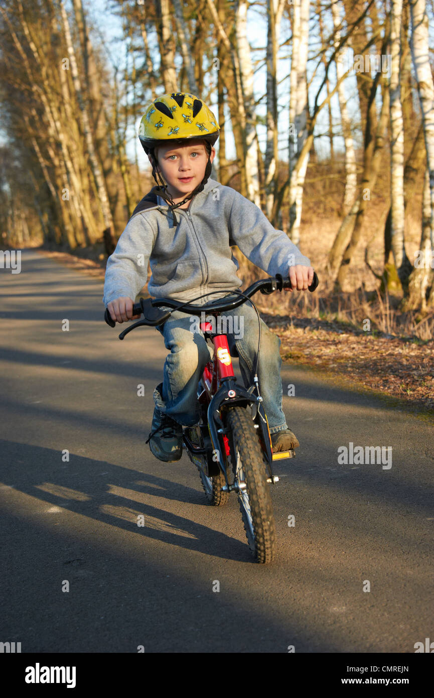 Child blond boy 5 years old riding bicycle with safety helmet in