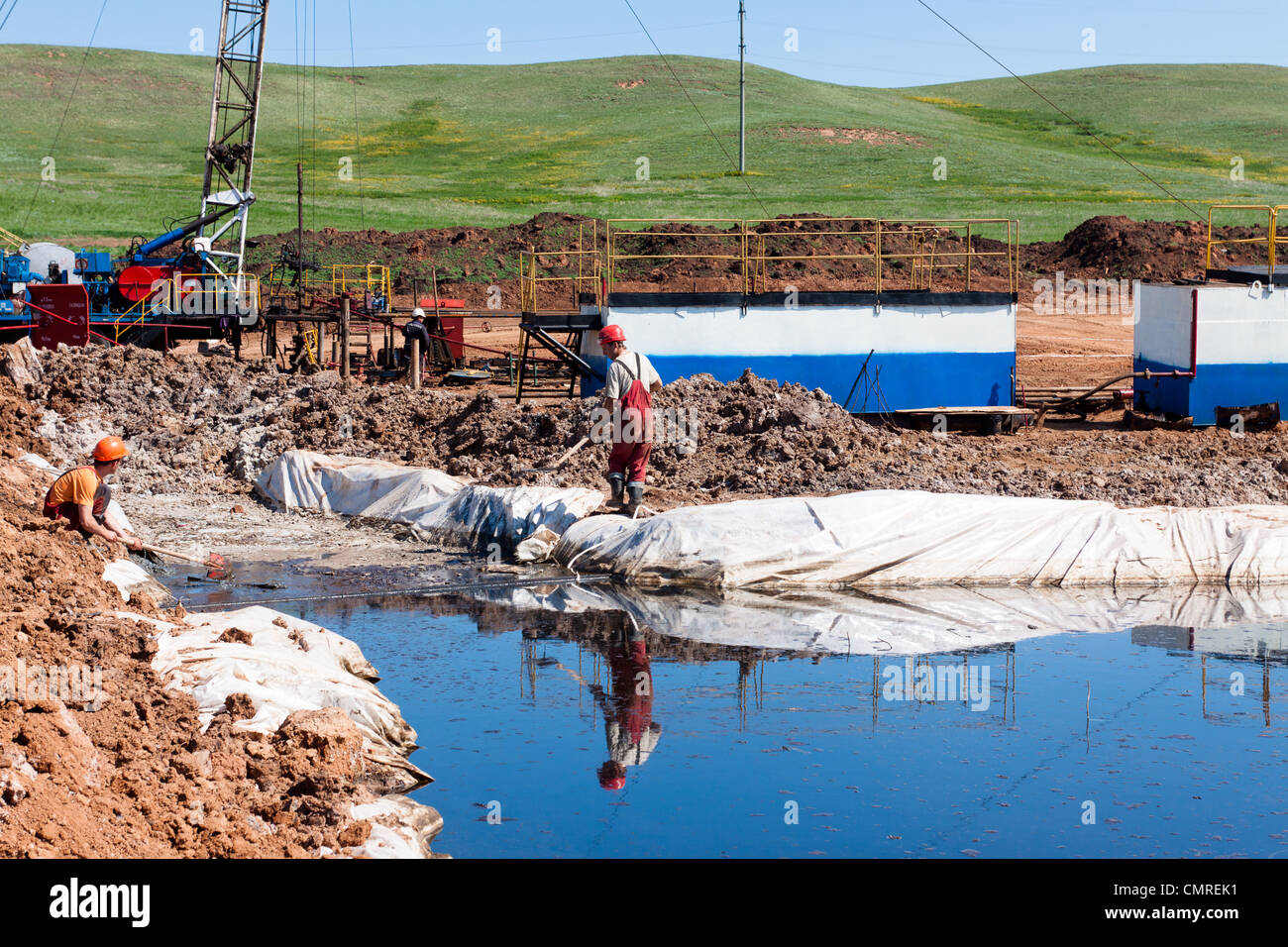 Workers collected oil and debris from the surface of the drilling waste water. Stock Photo