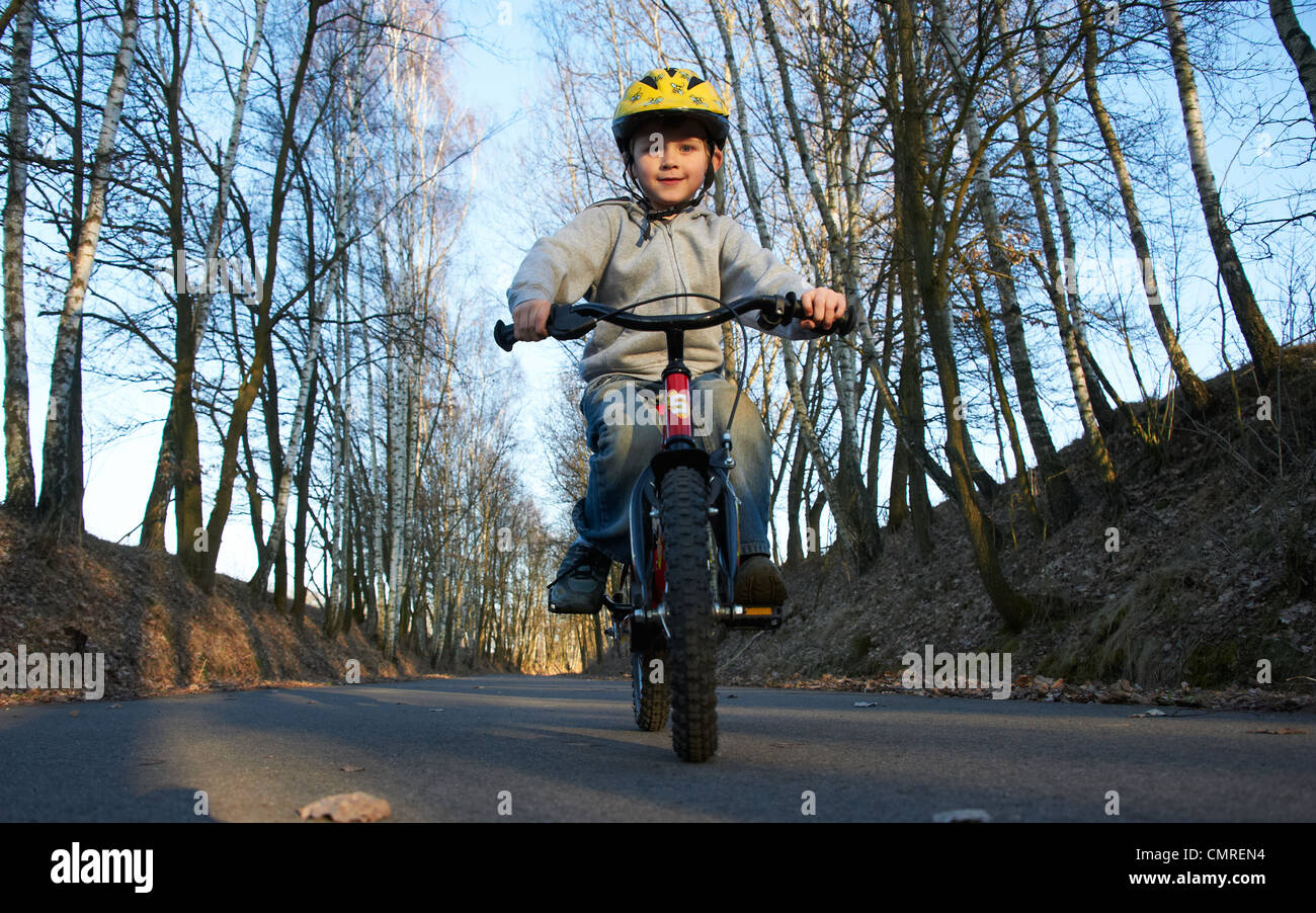 Child blond boy 5 years old riding bicycle with safety helmet in