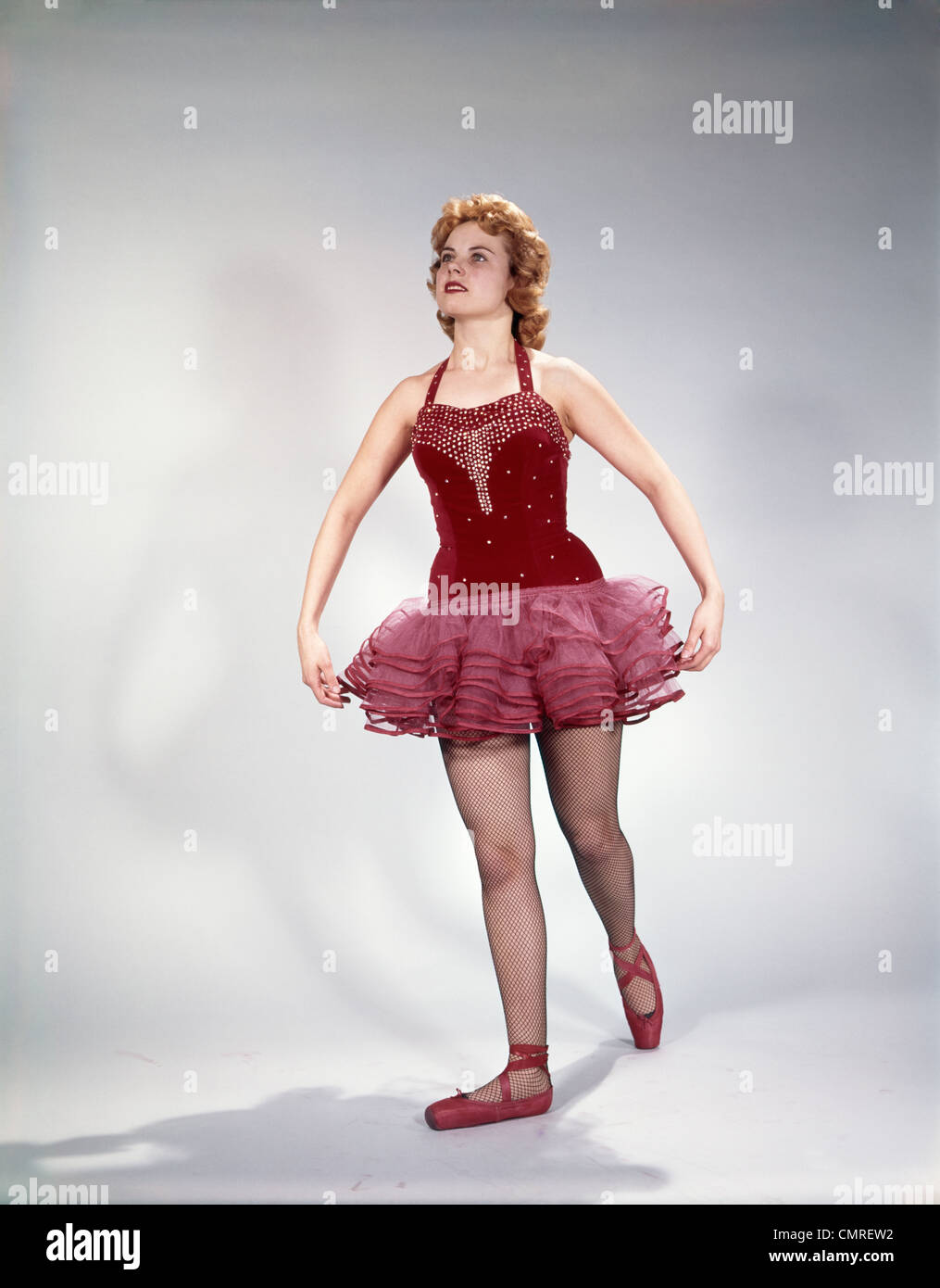 1960s AWKWARD TEENAGE GIRL DANCER IN RED VELVET TUTU COSTUME AND TOE SHOES Stock Photo