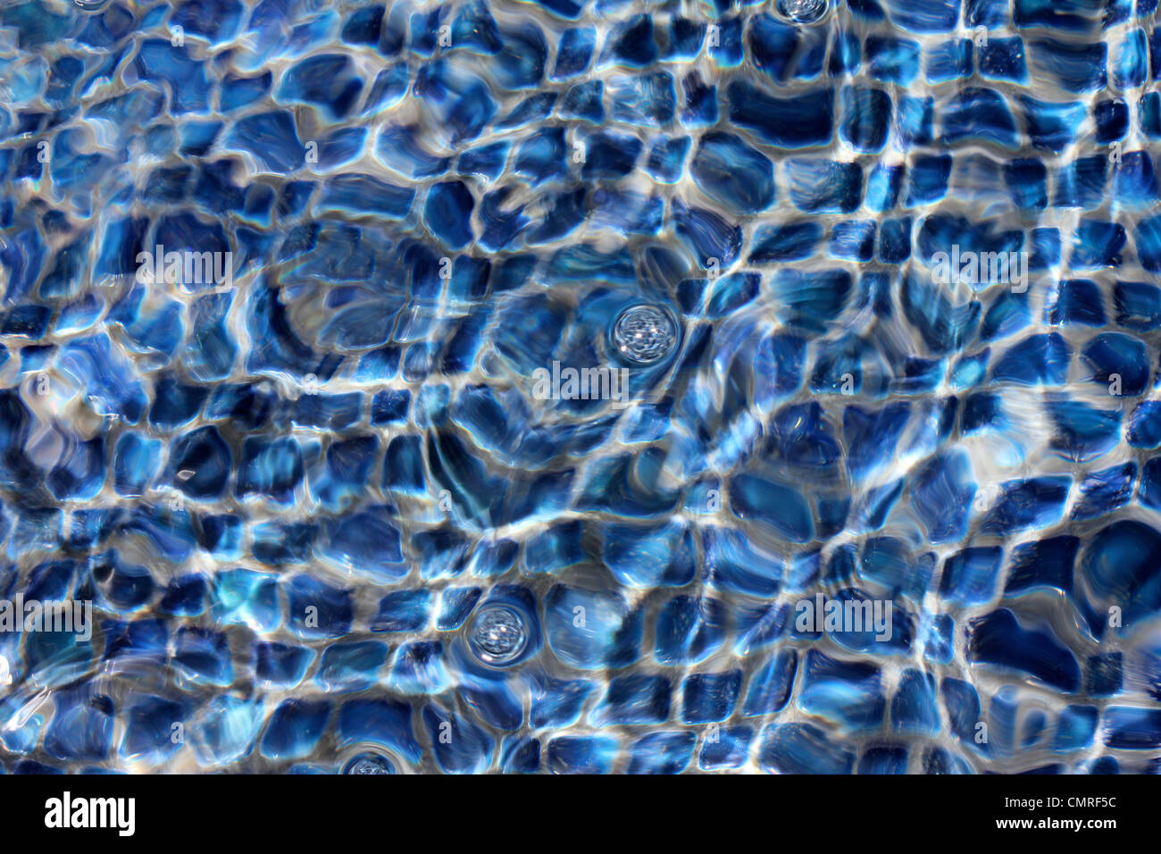 Clear water bubbling over blue and white tiles Stock Photo