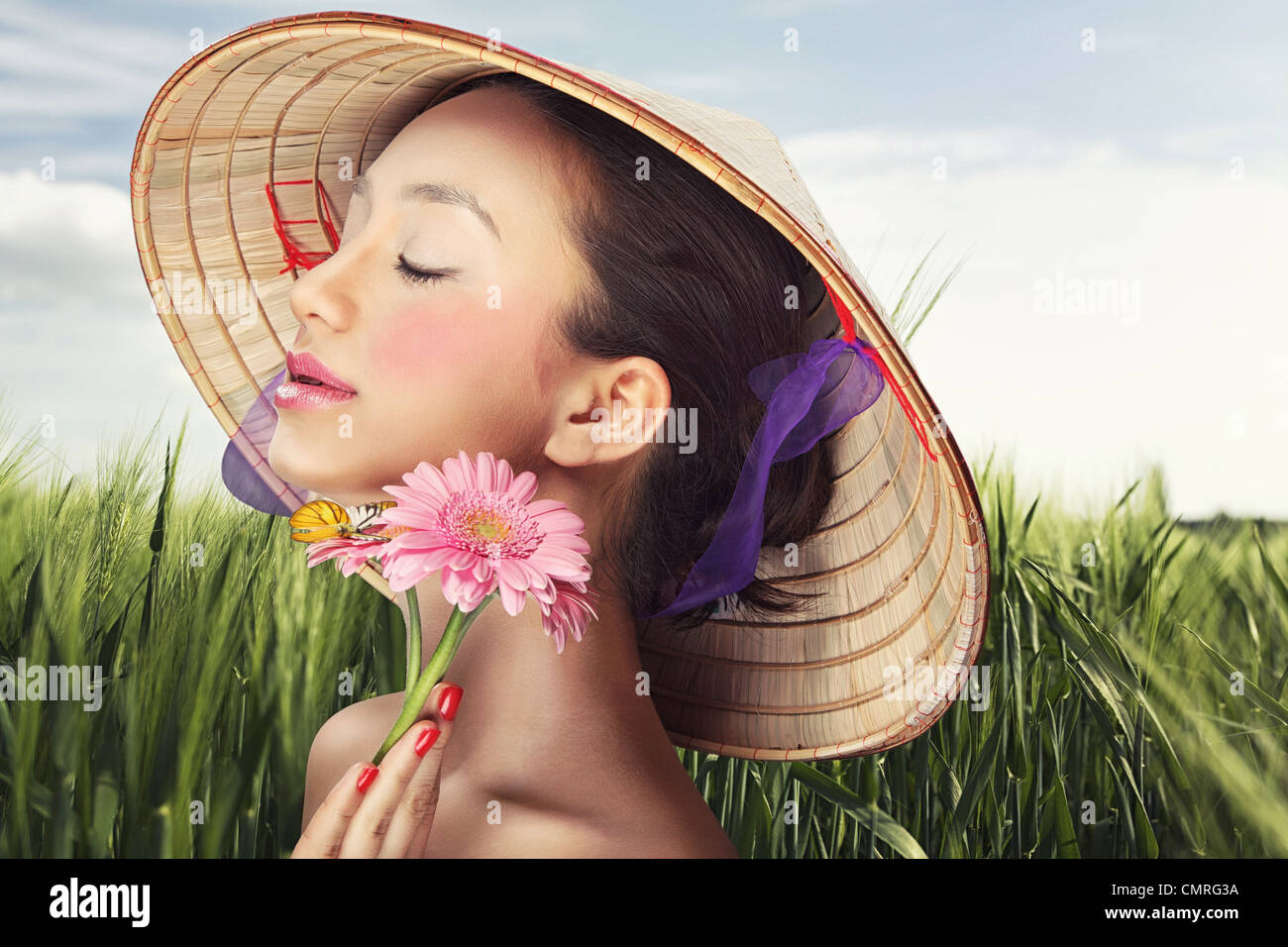 Beautiful Vietnamese girl in a traditional hat is holding flowers Stock