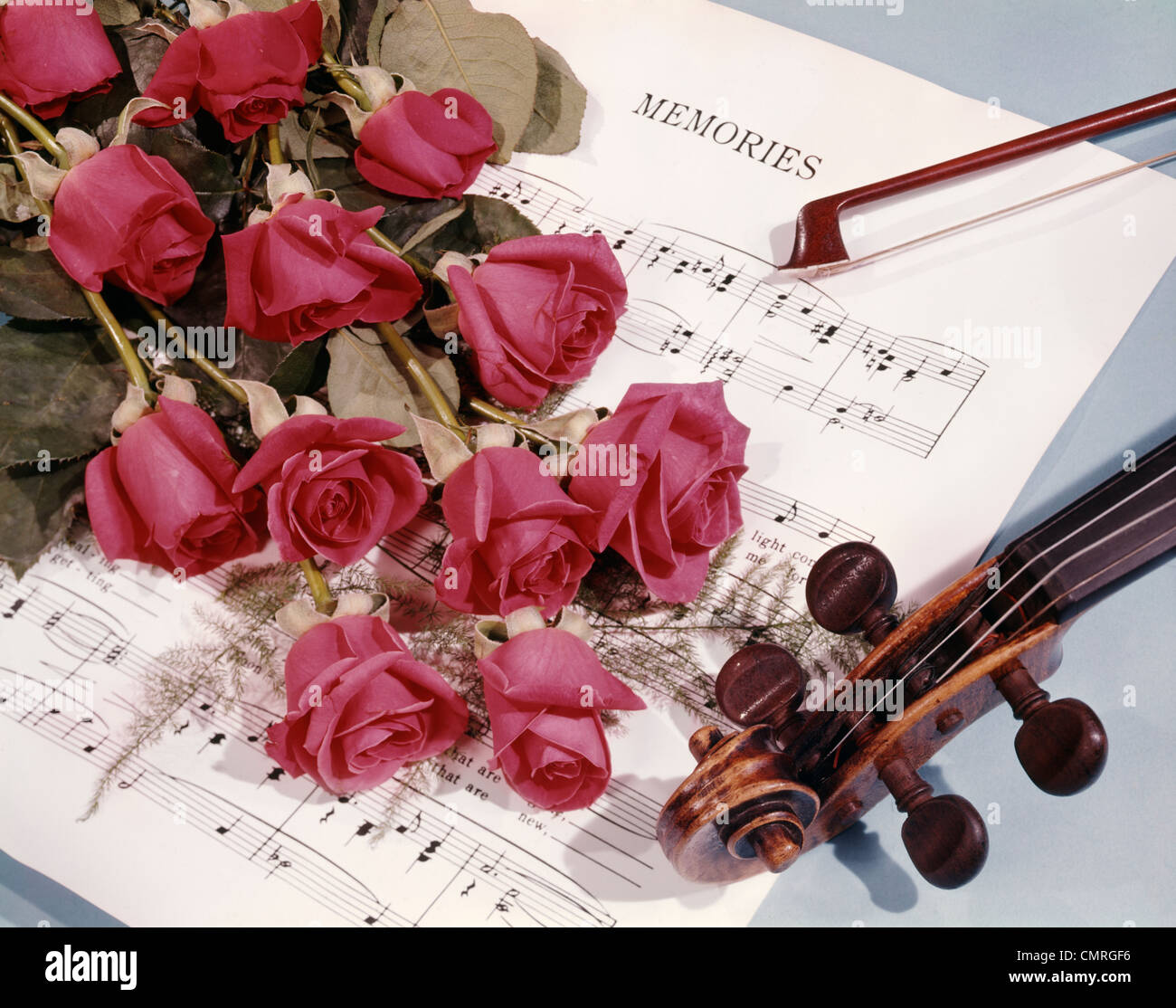 1960s STILL LIFE VIOLIN WITH BOUQUET OF RED ROSES ON TOP OF MEMORIES SHEET MUSIC Stock Photo