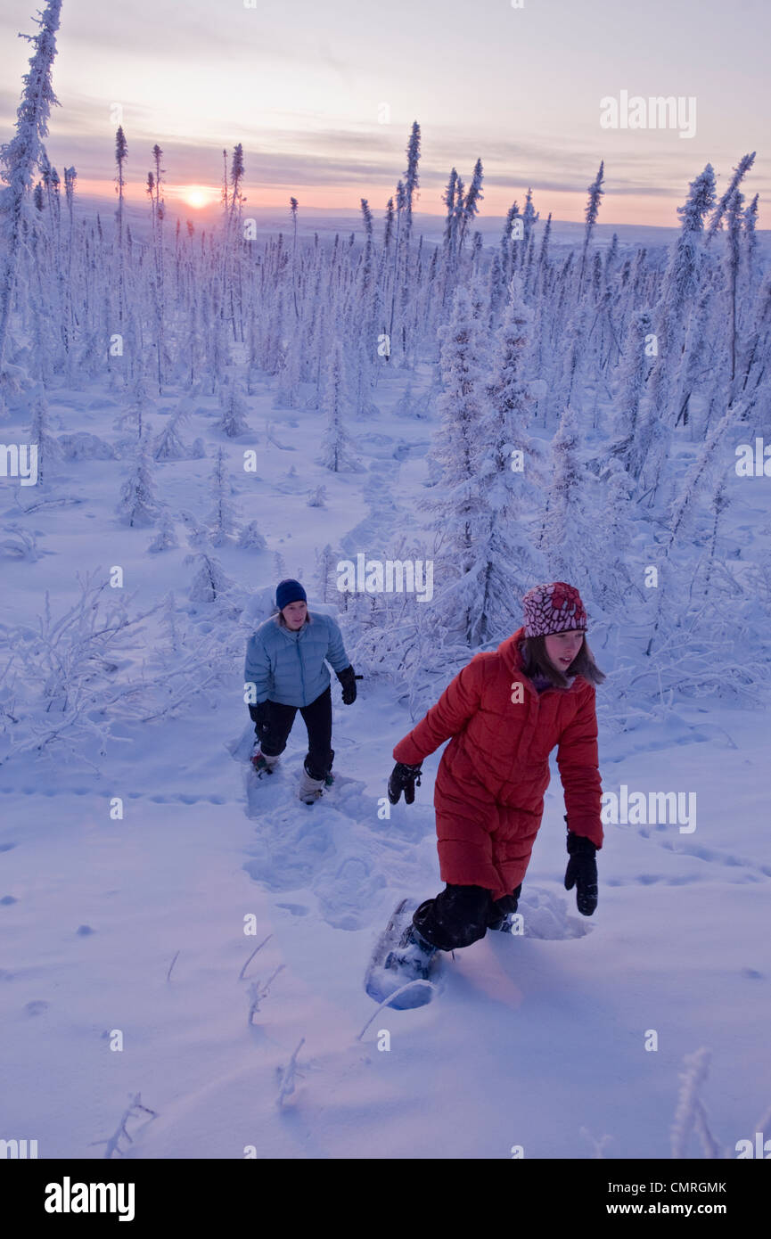 Mother and Daughter hiking in snowshoes through snowcovered forest