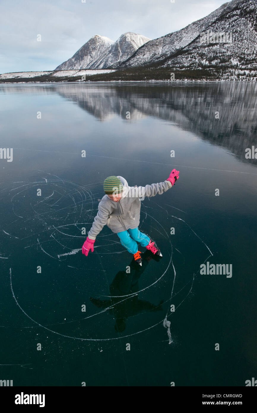Girl skating on frozen lake in winter, Kusawa Lake Territorial Park