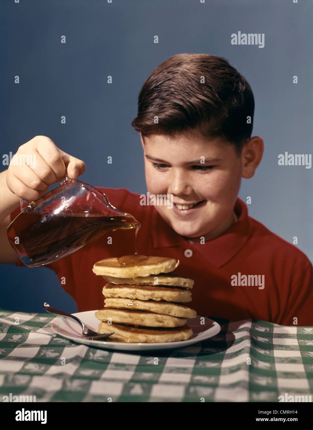 1950s 1960s SMILING BOY POURING SYRUP ON BREAKFAST PANCAKES Stock Photo Alamy
