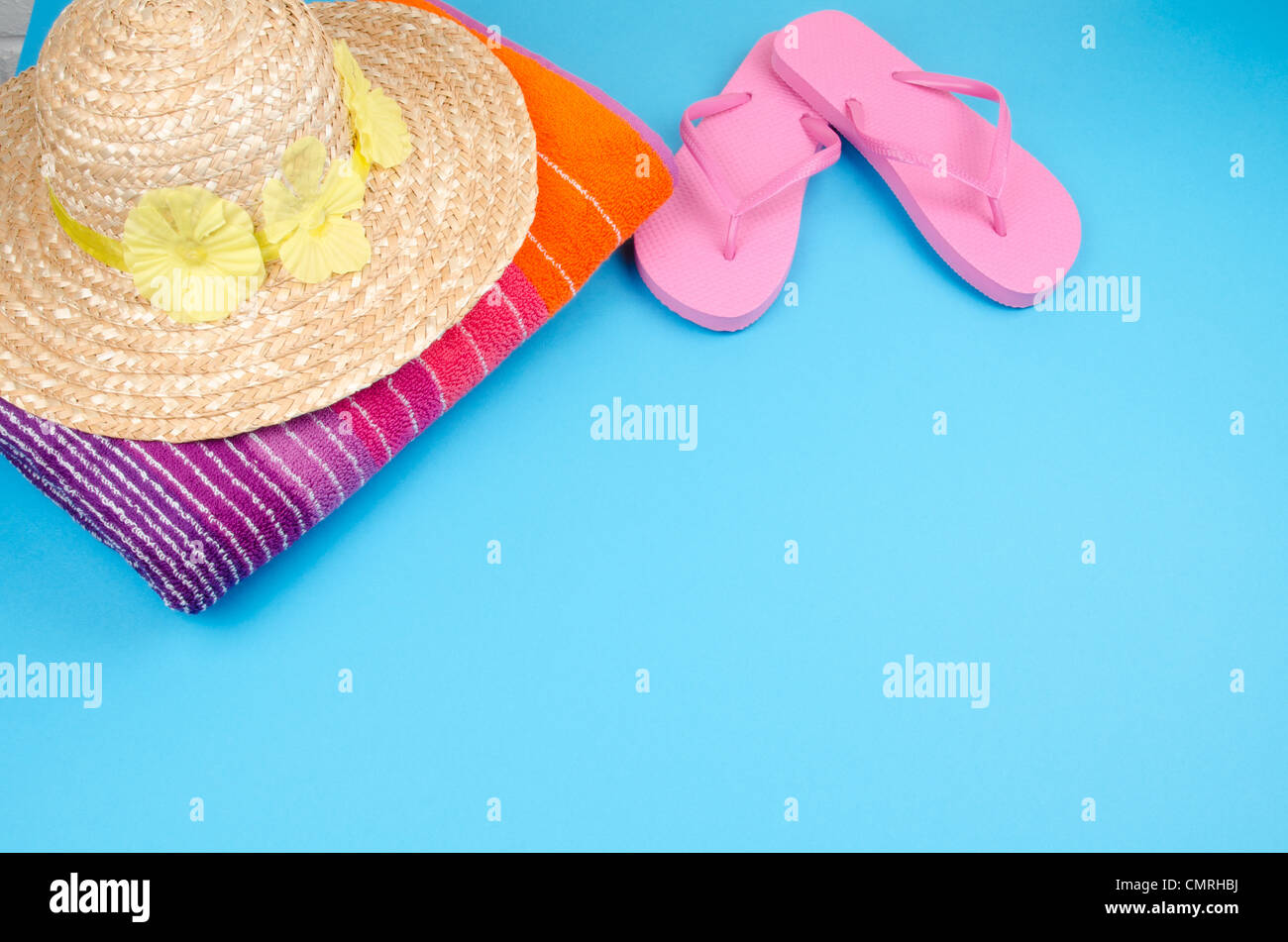 Pink flip-flops on a blue background with a sun hat and beach towel ...