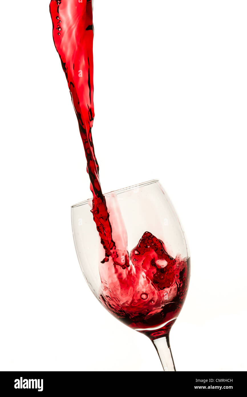 Glass filled with a large stream of red wine on white background Stock