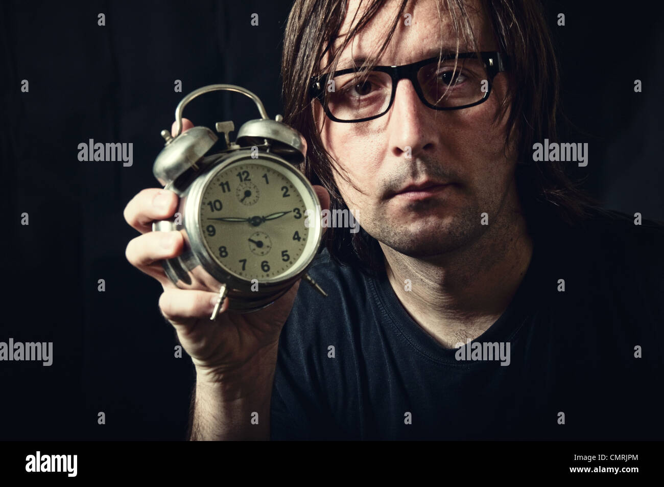 Adult man holding a vintage clock in low light interior Stock Photo