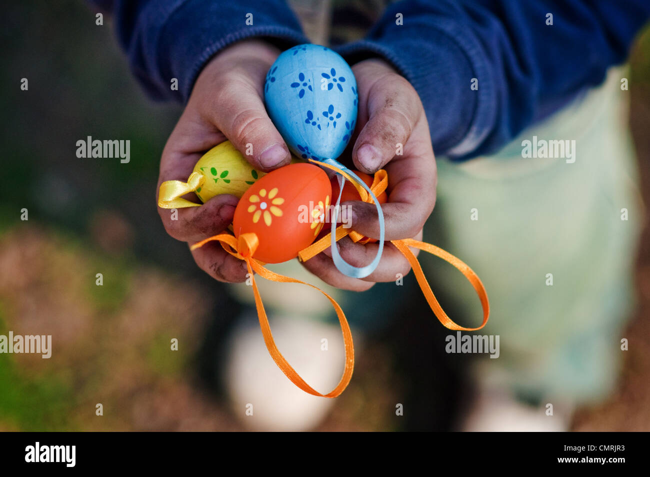 Plastic easter eggs in small, dirty child's hands. Poverty concept. Stock Photo