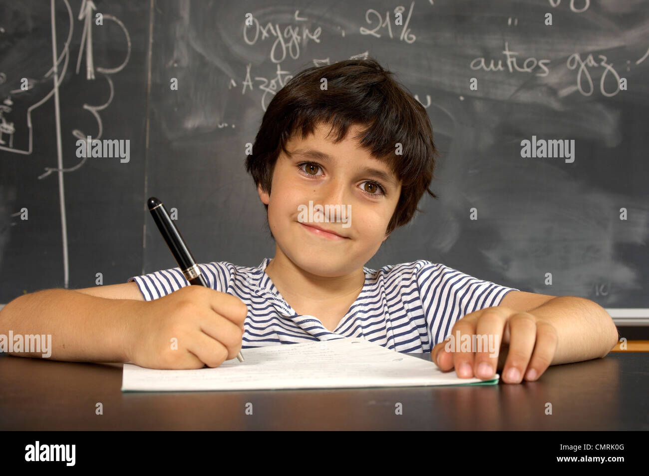 Boy Writing at Desk in Classroom Stock Photo - Alamy