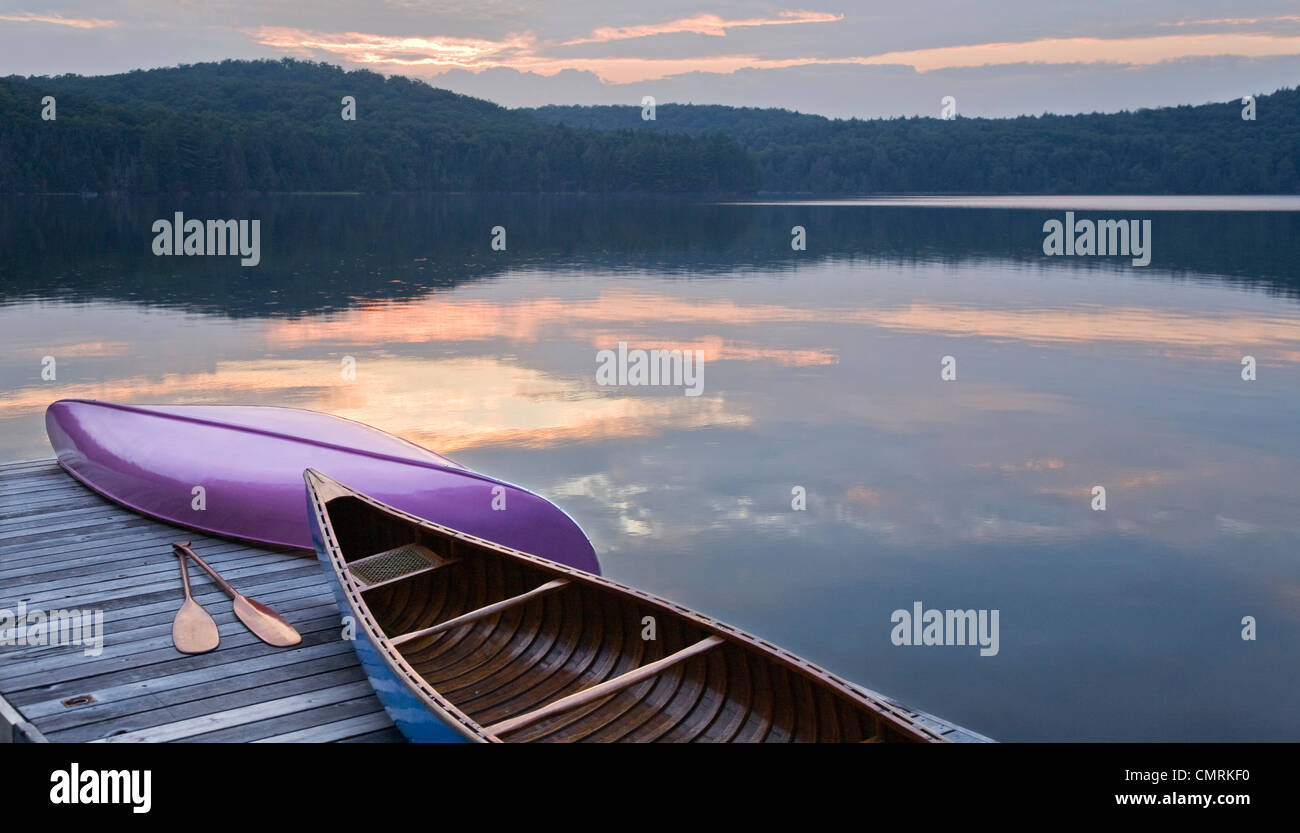 Canoes and paddles on dock at sunset, Smoke Lake, Algonquin Park, Ontario Stock Photo
