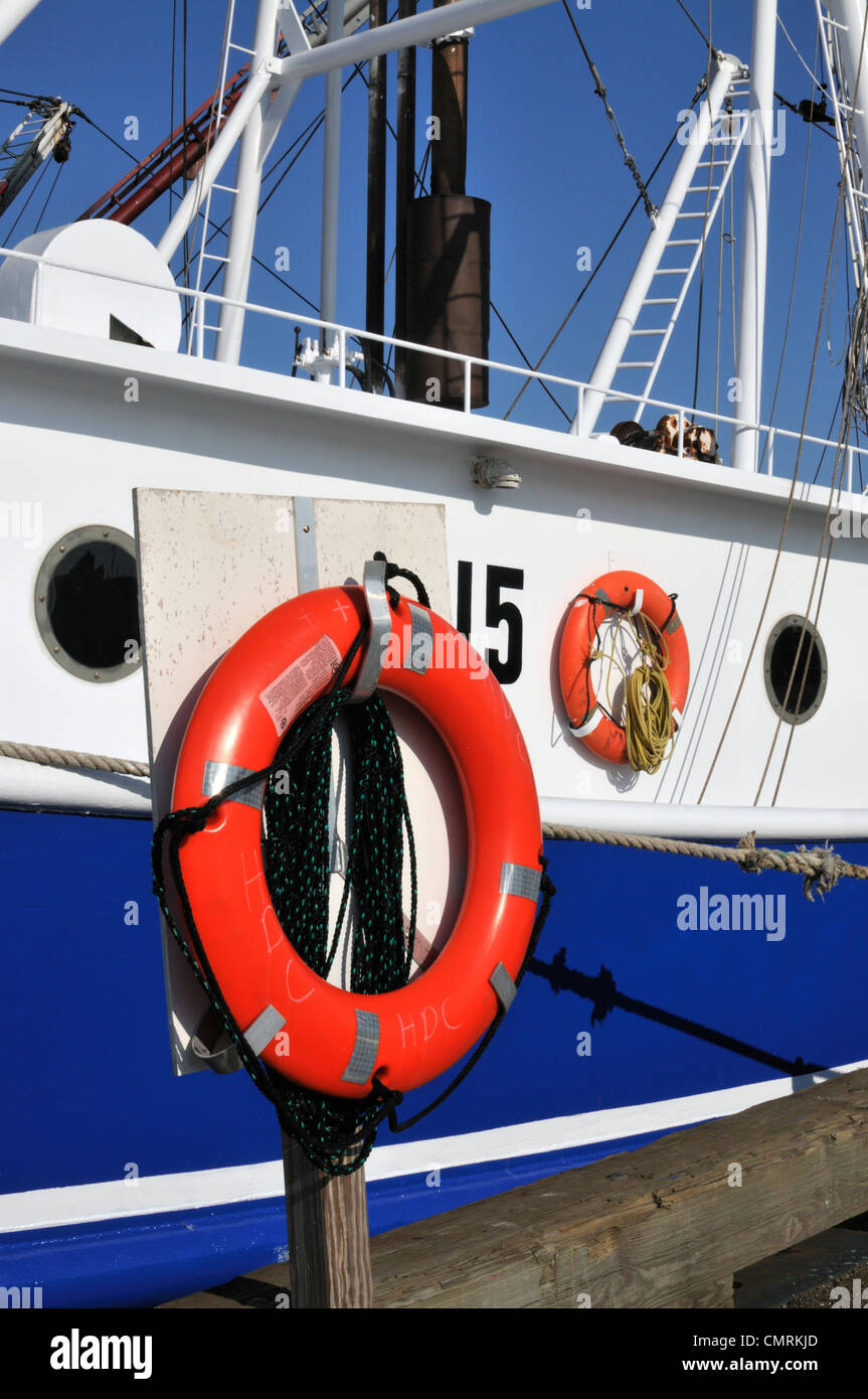 Orange life saving ring buoy on side of commercial fishing boat in New Bedford Harbor