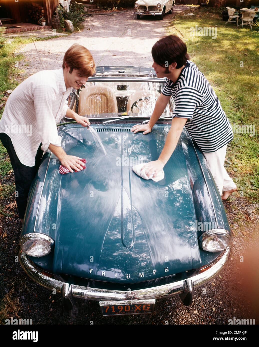 1970s TWO TEENAGED BOYS WASHING TRIUMPH SPORTS CAR  CONVERTIBLE Stock Photo