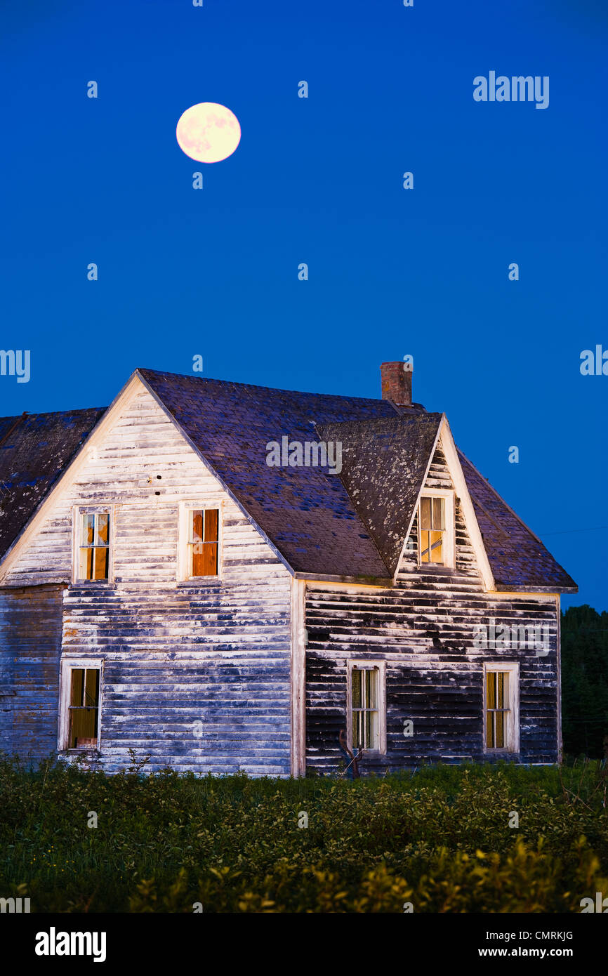 Abandoned house and moon at dusk, Perce, Gaspesie, Quebec Stock Photo