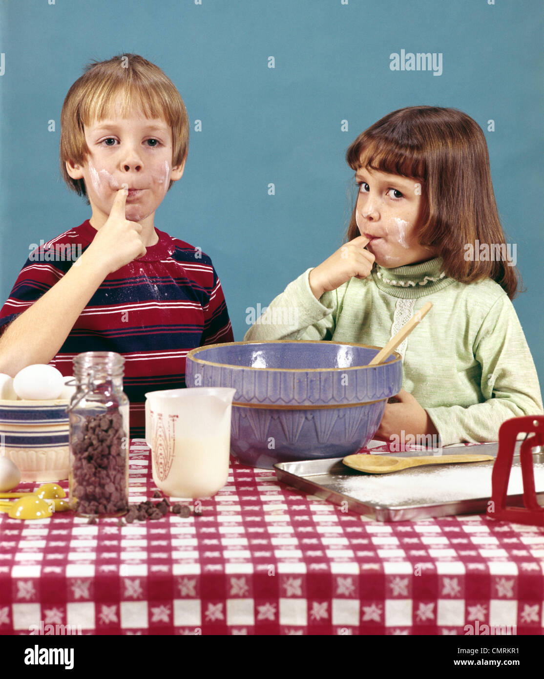 1970 1970s RETRO BOY GIRL BROTHER SISTER MAKING COOKIES TASTING BATTER CHOCOLATE CHIPS BAKING COOKING Stock Photo