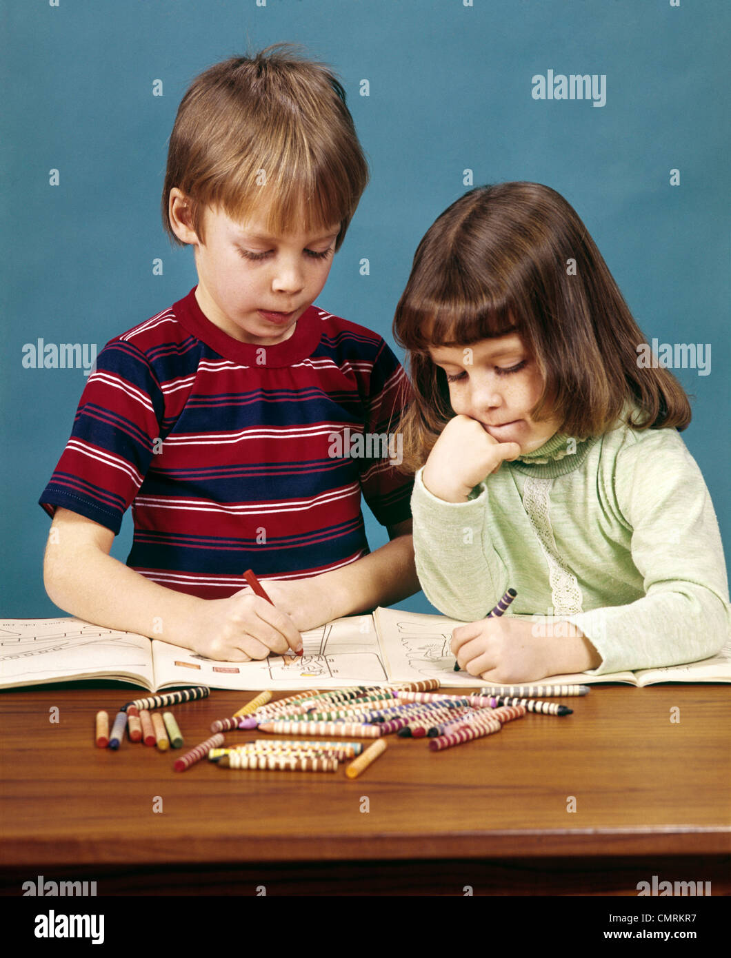 1970 1970s RETRO BOY GIRL BROTHER SISTER COLORING DRAWING IN COLORING BOOKS WITH CRAYONS Stock Photo