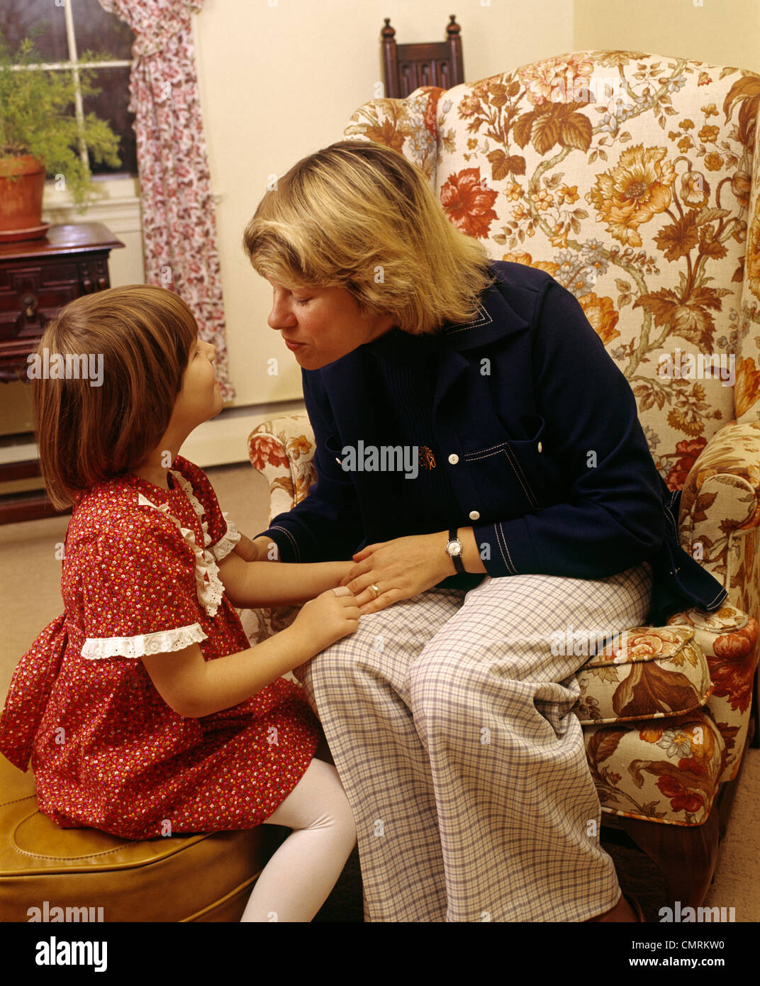 1970 1970s RETRO MOTHER SITTING IN ARMCHAIR SMILING TALKING TO DAUGHTER Stock Photo