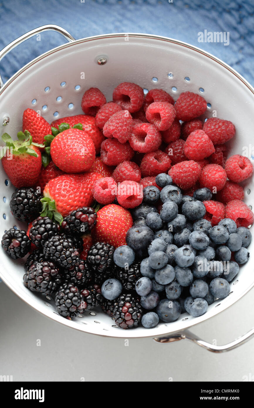 Various fresh berries in colander Stock Photo