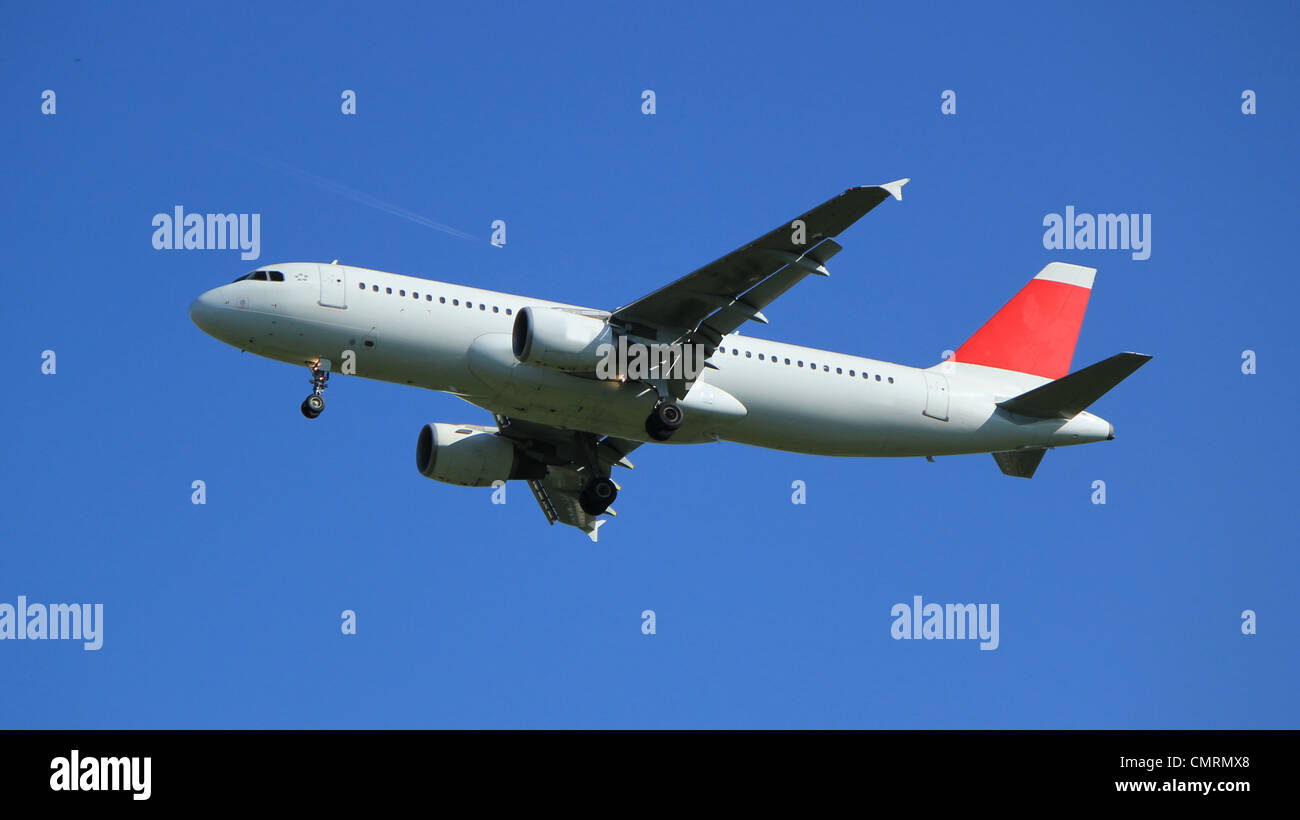 White and red flying plane in the blue sky with another very small