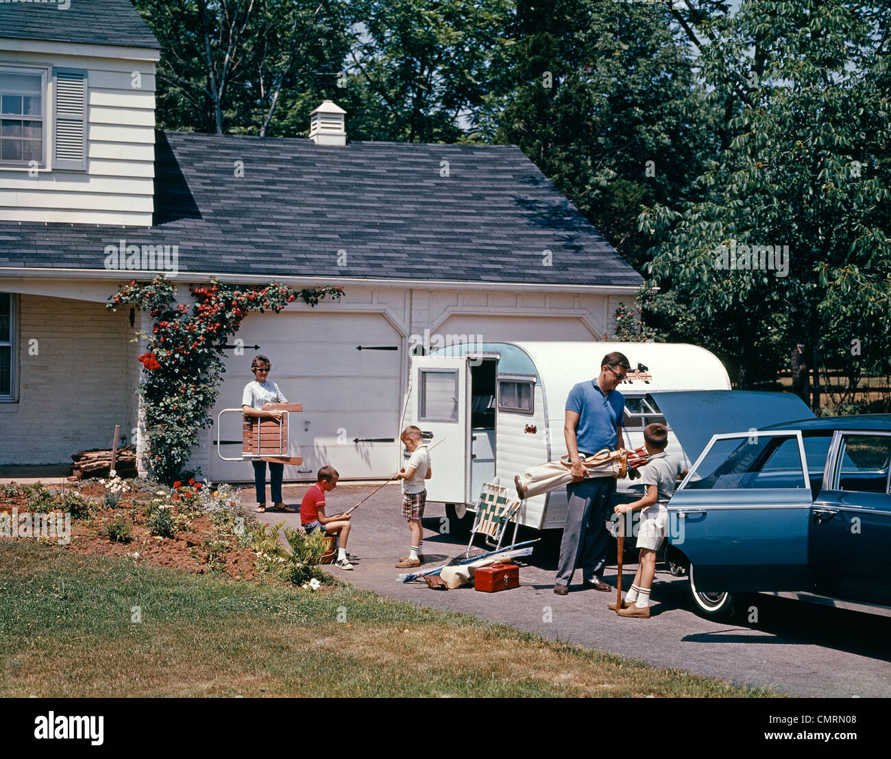 1960s FAMILY FATHER MOTHER SON DAUGHTER LOADING CAR AND TRAILER FOR VACATION SUMMER OUTDOOR Stock Photo