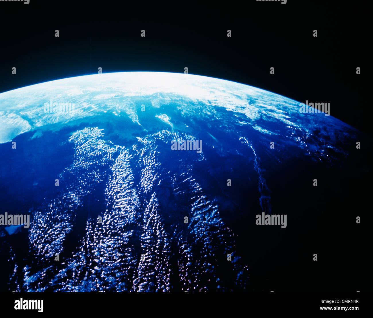 EARTH FROM OUTER SPACE SHOWING BLUE OCEAN SURFACE WITH CLOUDS AND CURVED HORIZON Stock Photo