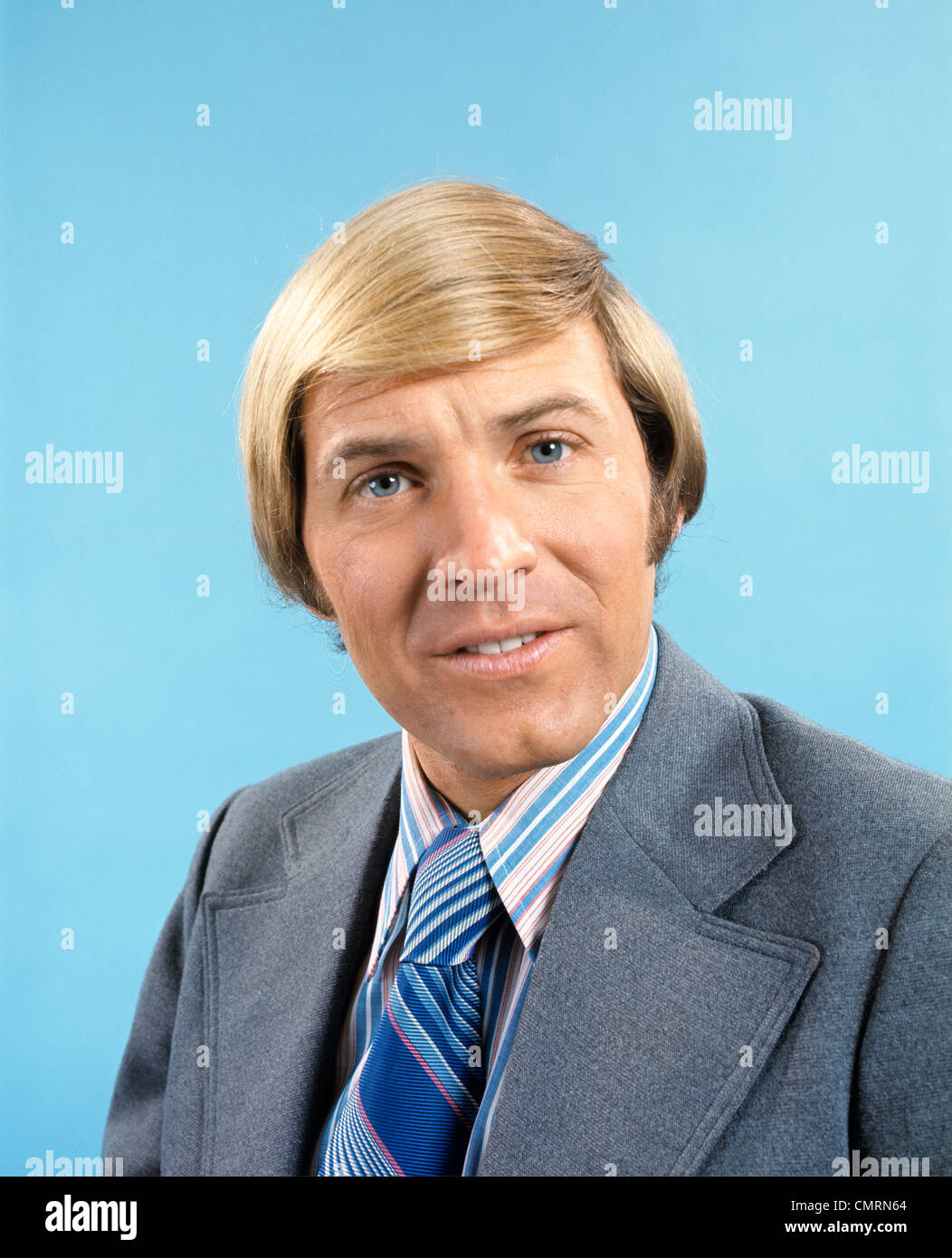 1970 1970s RETRO PORTRAIT OF BLONDE MAN WEARING GREY SUIT BLUE STRIPED TIE Stock Photo