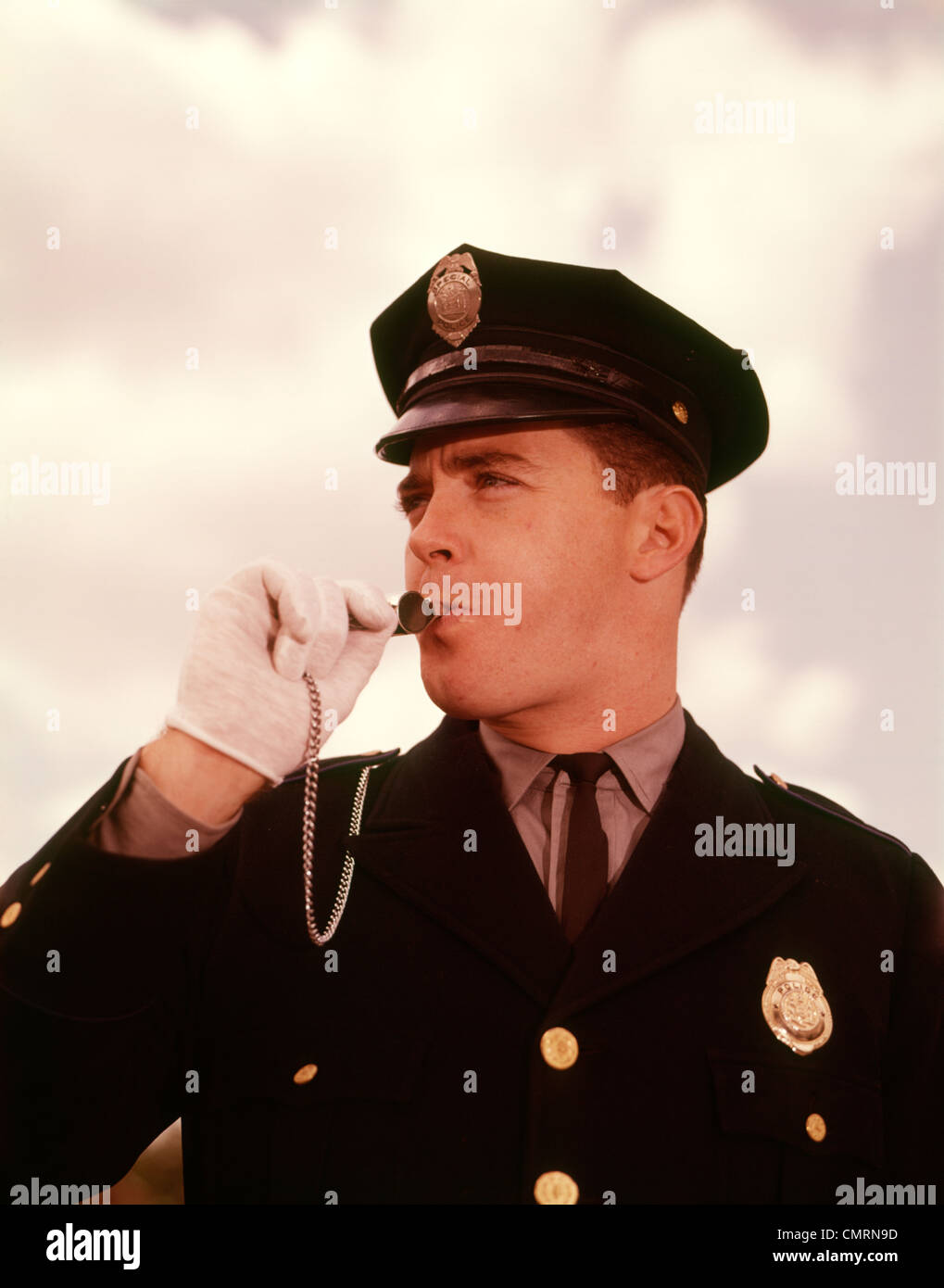 1950 1950s 1960 1960s HEAD SHOT POLICE POLICEMAN TRAFFIC COP BLOWING WHISTLE UNIFORM WHITE GLOVES MAN MEN RETRO Stock Photo