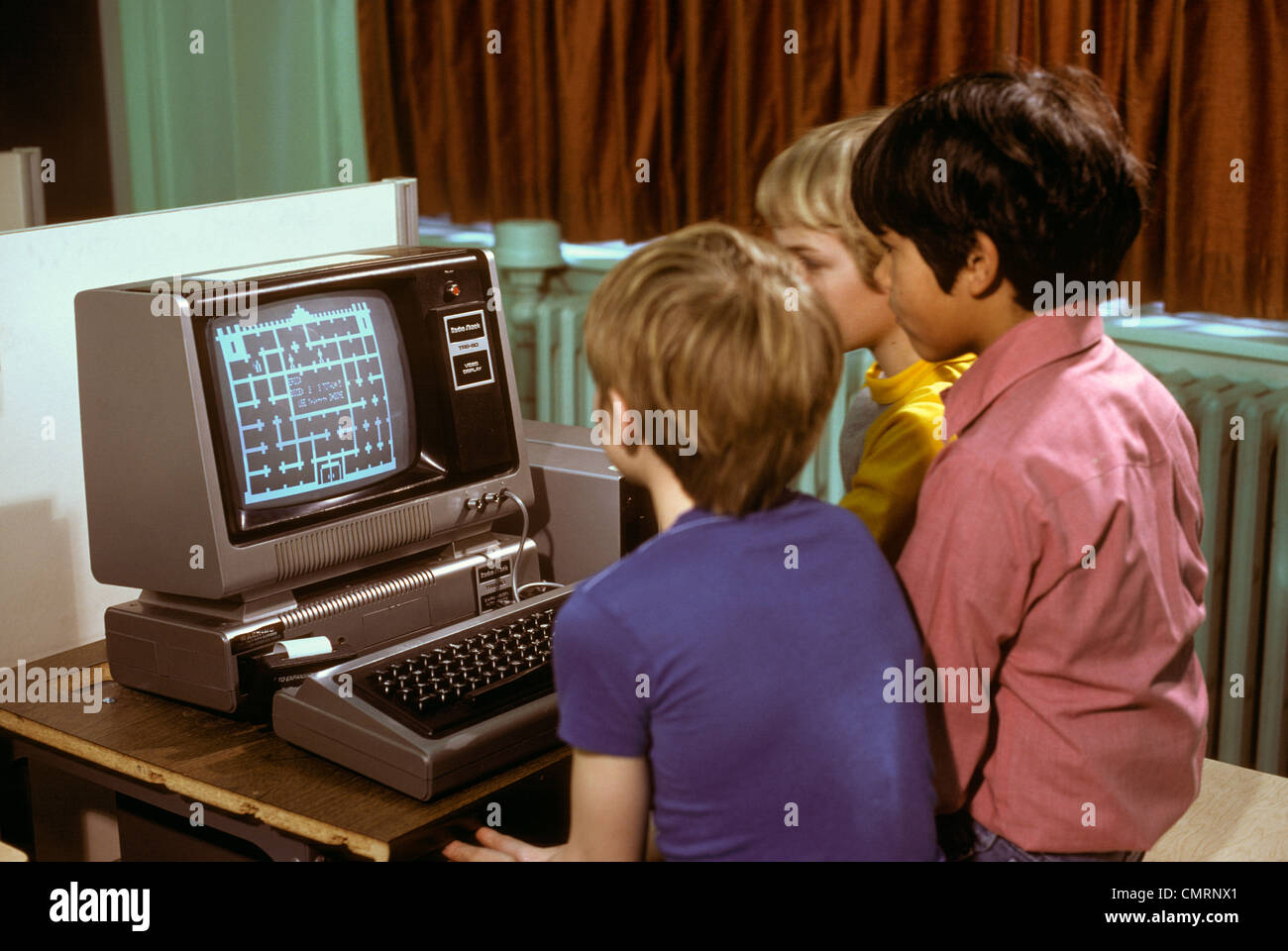1980s 3 ELEMENTARY SCHOOL BOYS OPERATING EARLY RADIO SHACK TRS80 COMPUTER PLAYING GAME Stock Photo